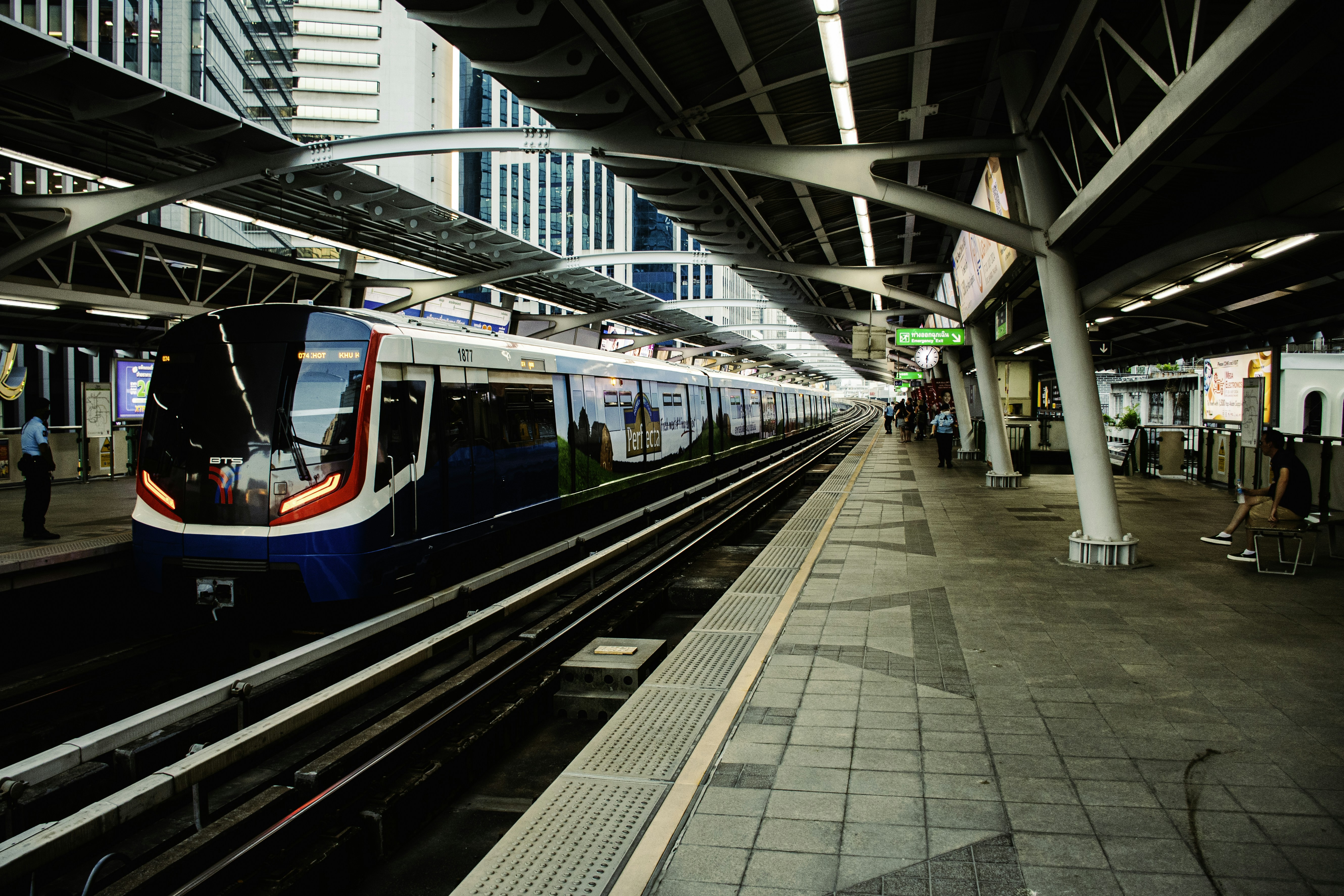 A train pulling into a train station next to tall buildings