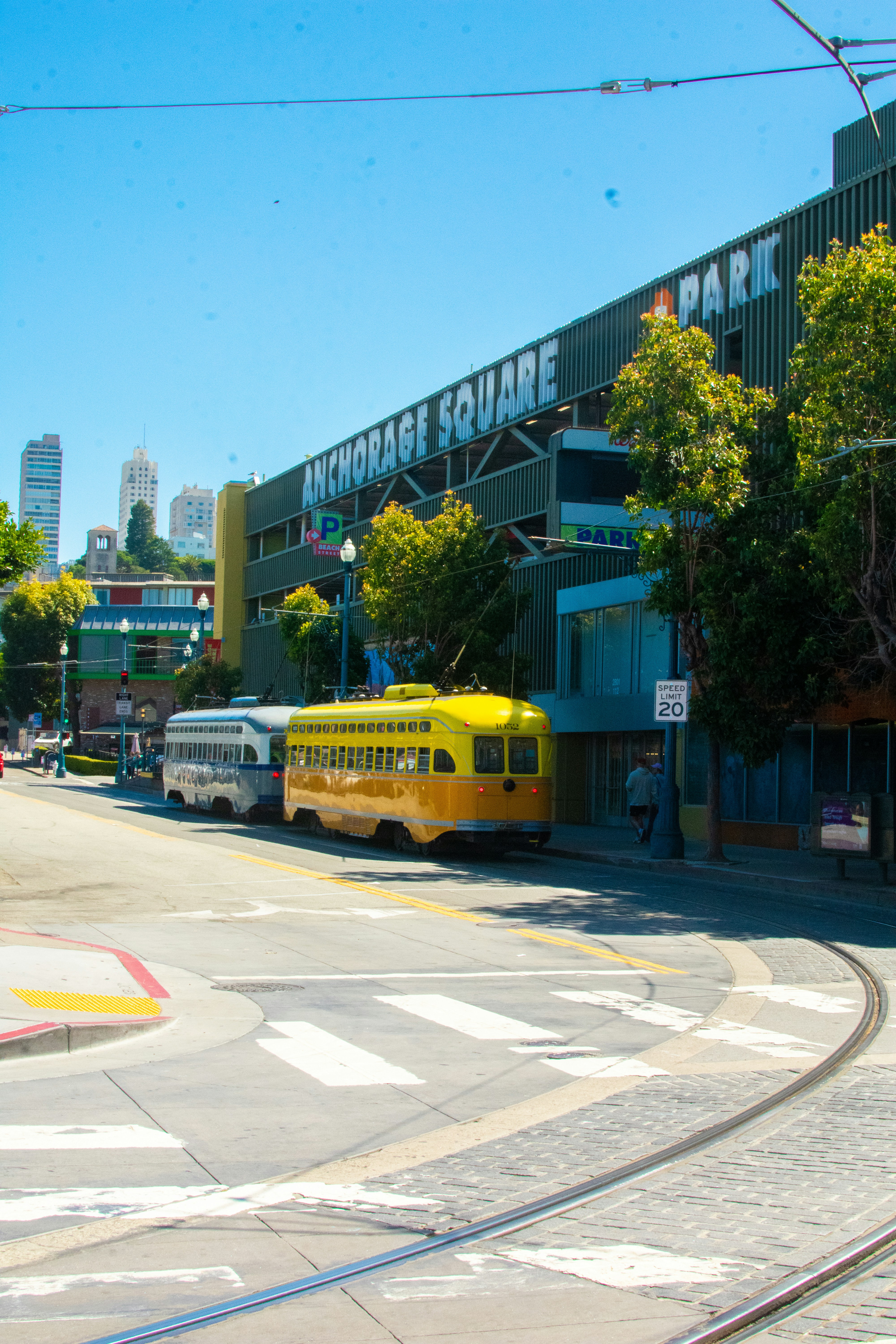 Um ônibus escolar amarelo dirigindo por uma rua ao lado de um prédio alto