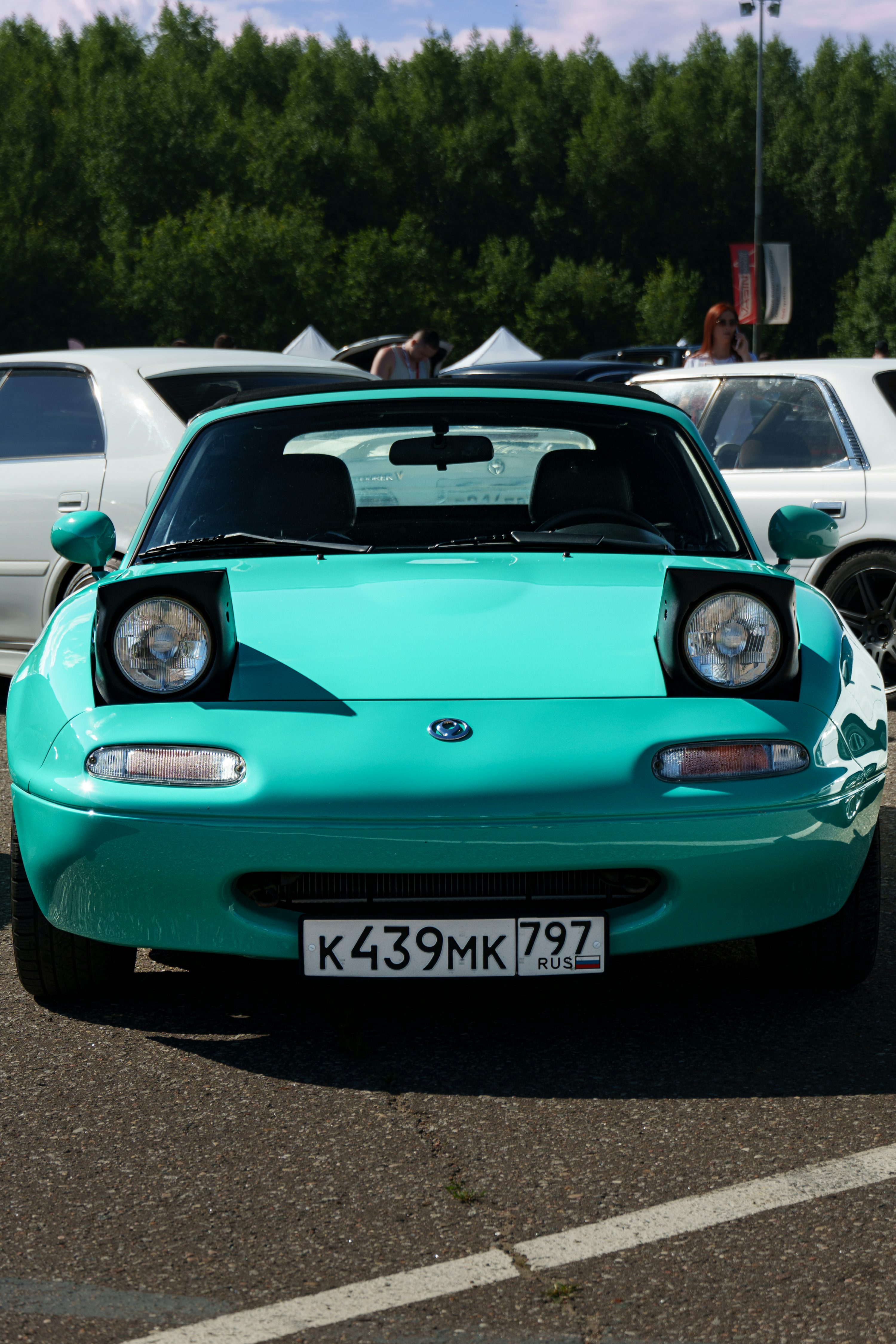 A blue car parked in a parking lot next to other cars