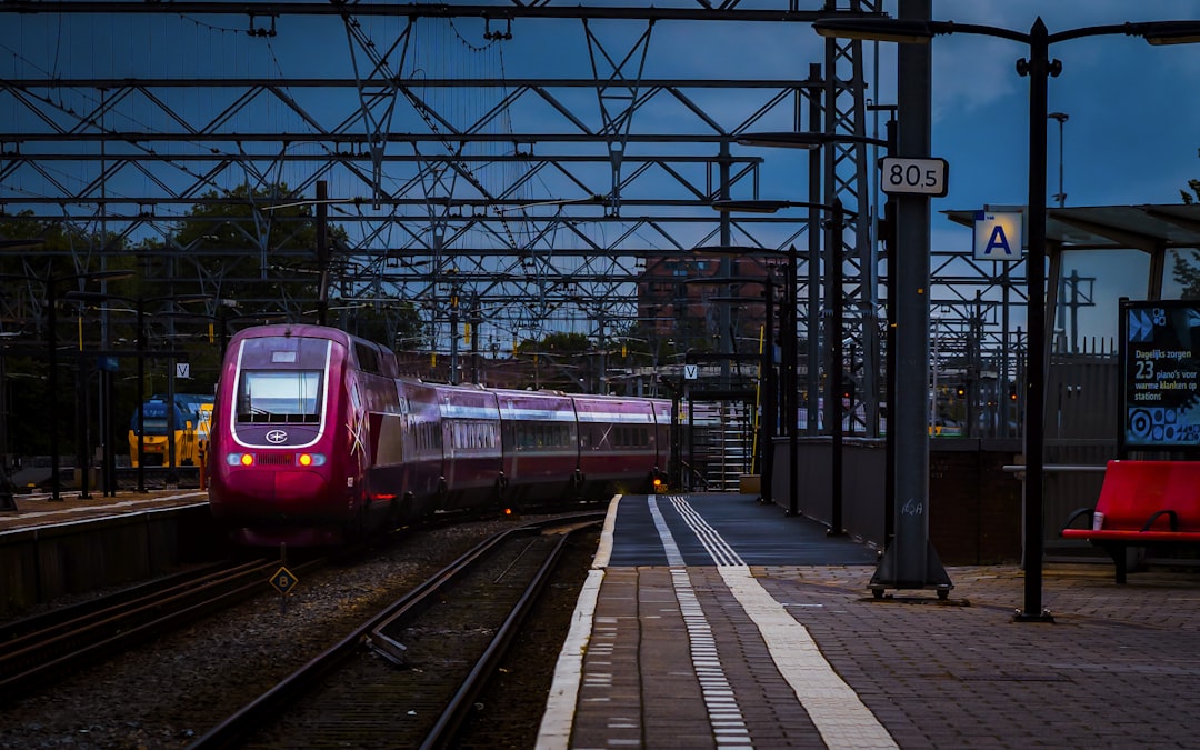 A red train traveling down train tracks next to a train station,
