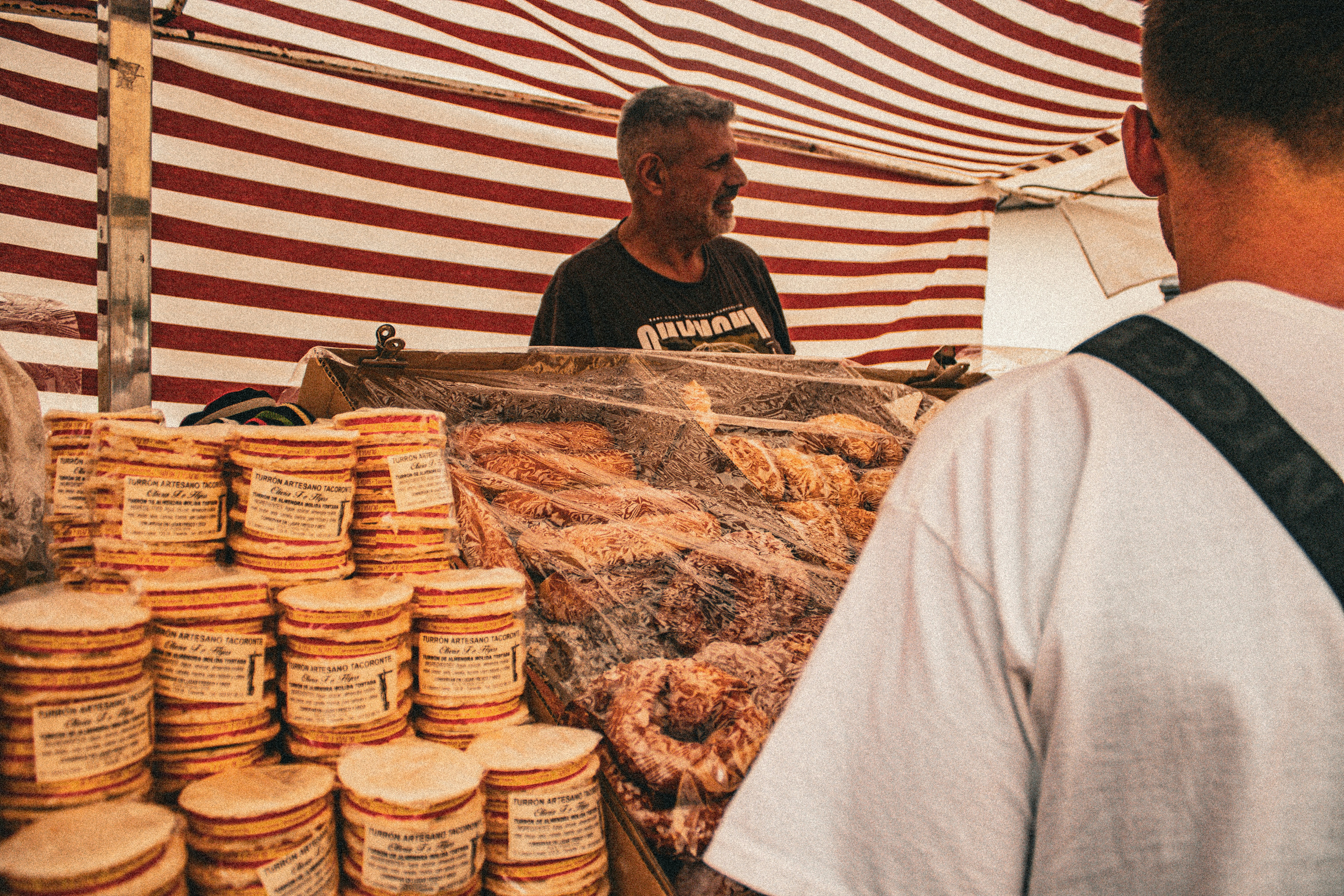 A man standing in front of a display of food, Tenerife celebrates the pilgrimage in the Canary Islands with vibrant traditions and colorful parades.