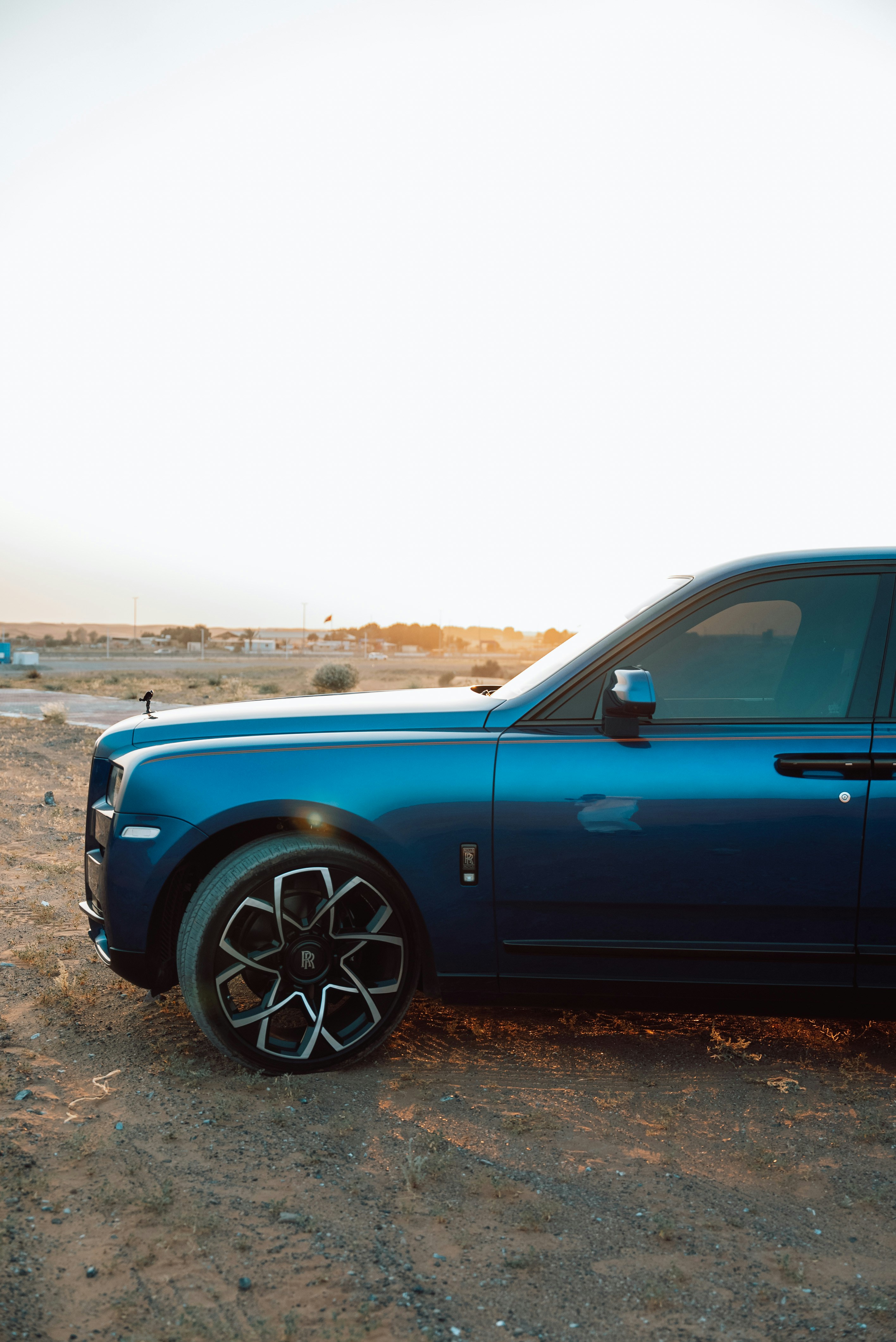 A blue car parked on a dirt road