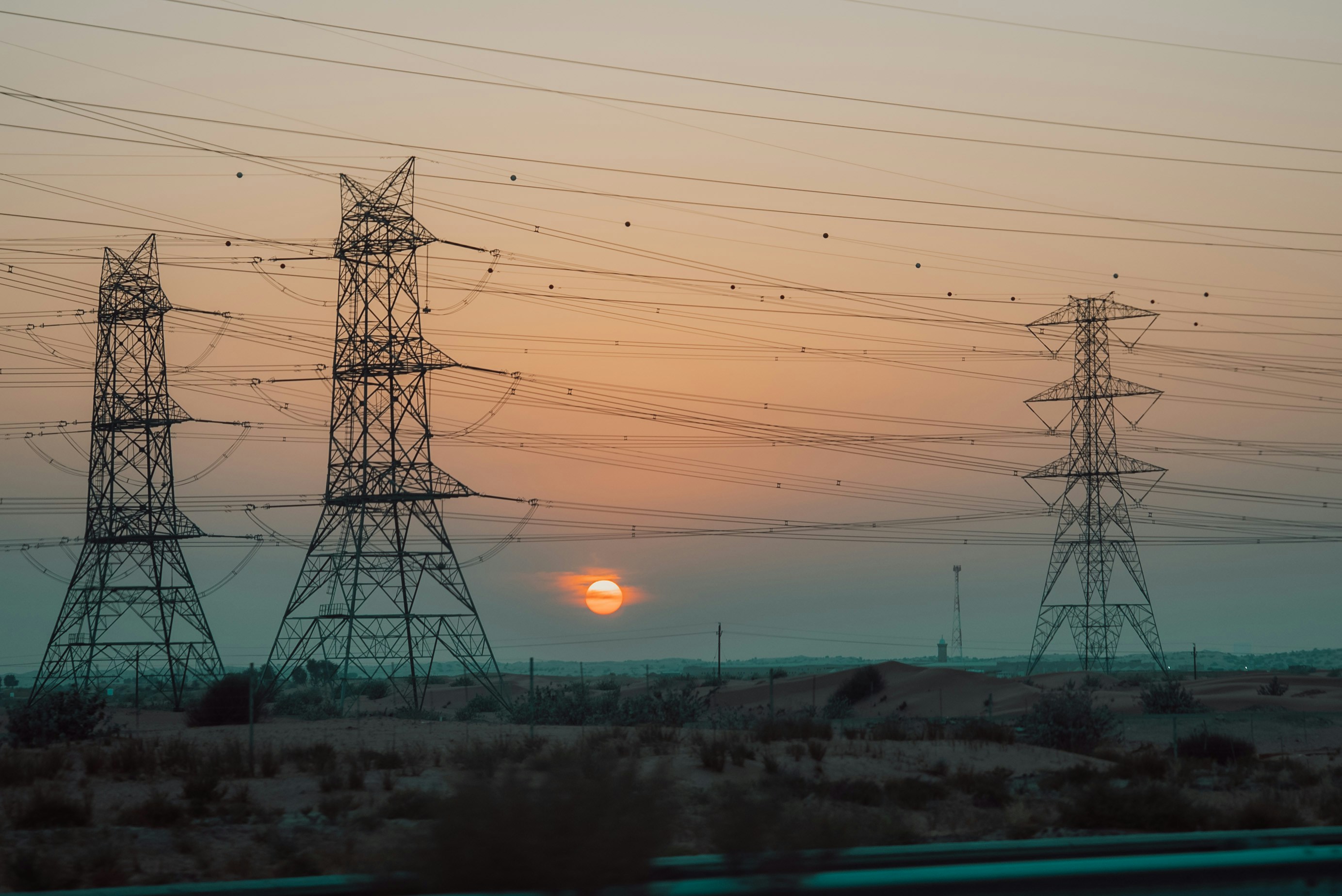The sun is setting behind the power lines
