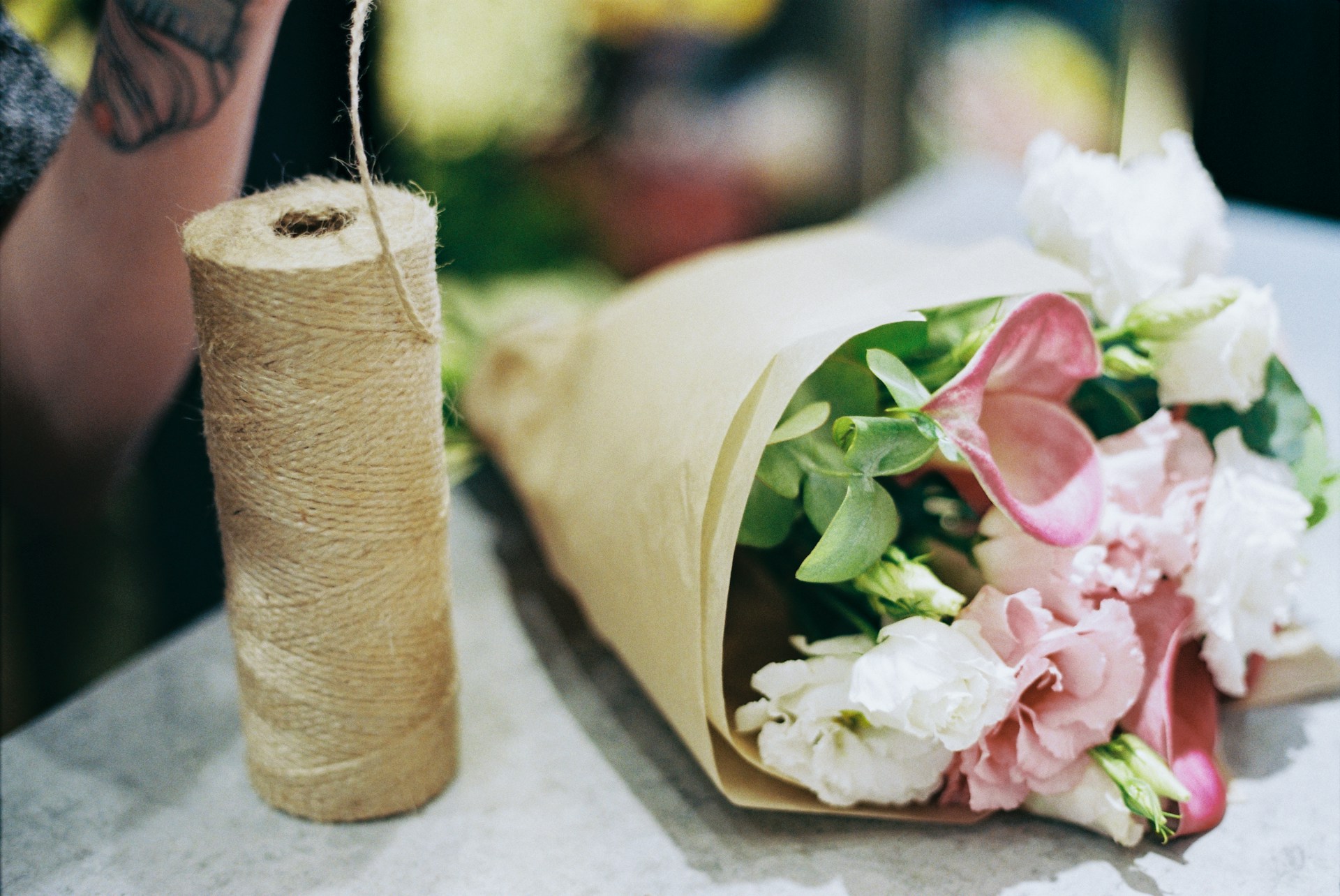 A rolled up flower bouquet sitting on top of a table next to a roll of