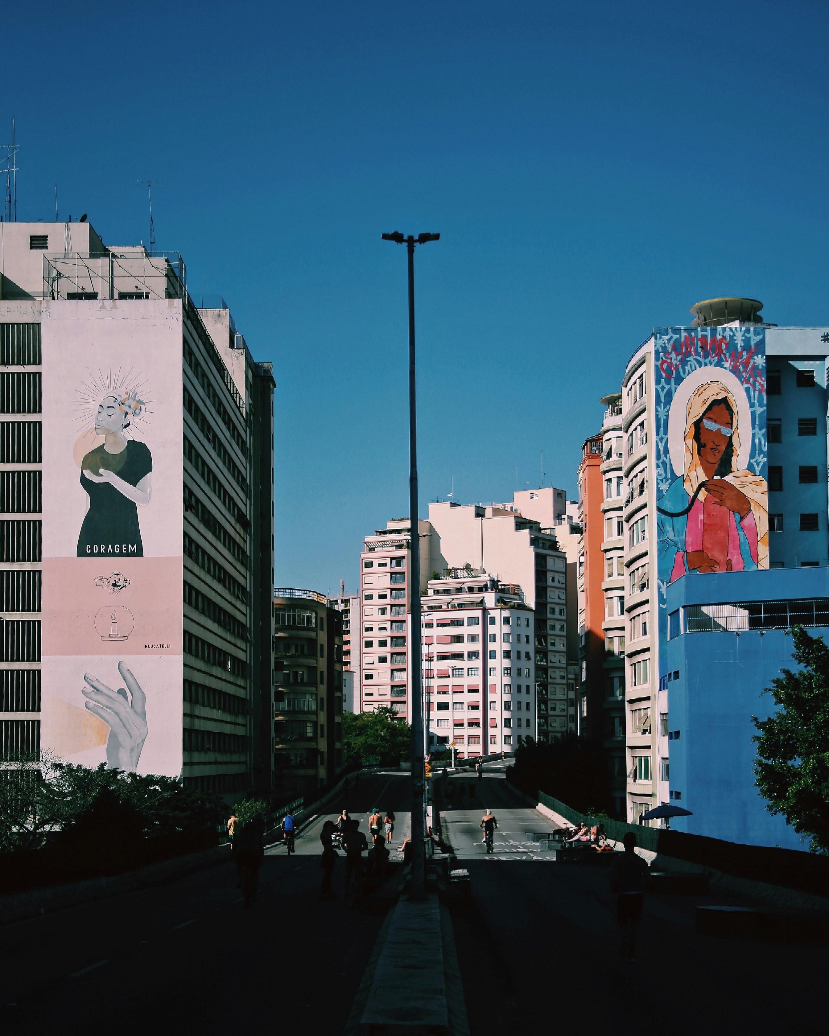 Une rue de la ville avec de grands immeubles et une fresque murale sur le côté