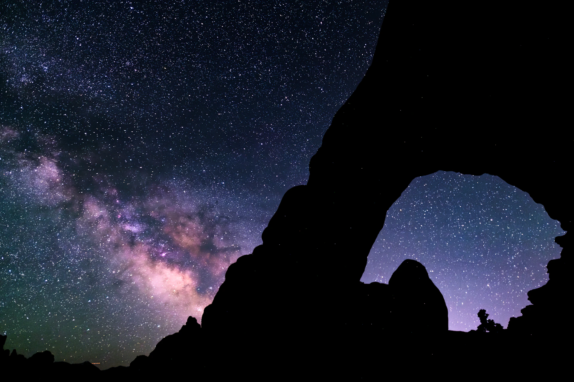 The silhouette of a rock formation against a night sky filled with stars