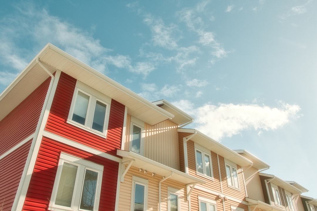 A row of multi - family houses with a blue sky in the background, IG:@studio_alexander