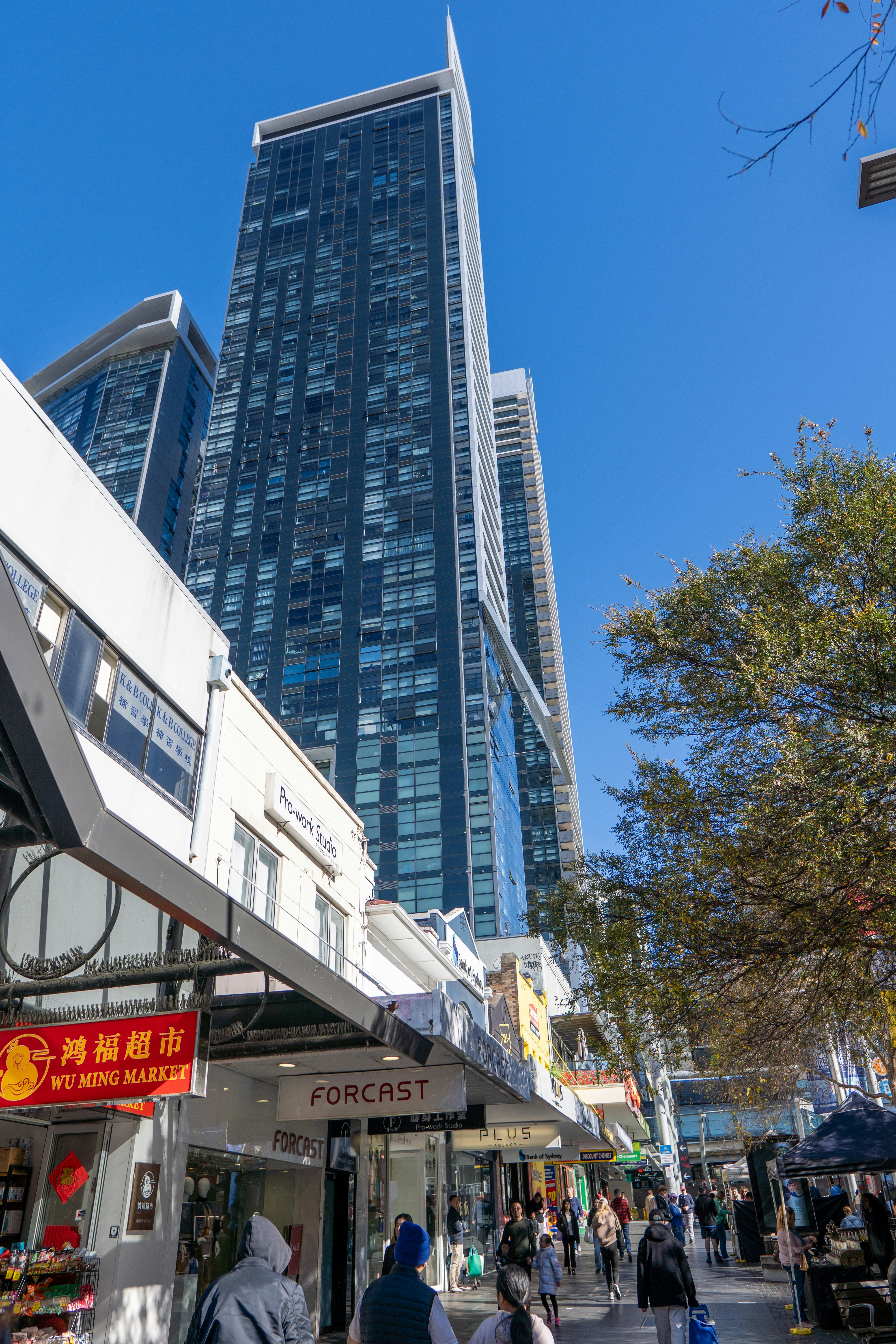 A group of people walking down a street next to tall buildings