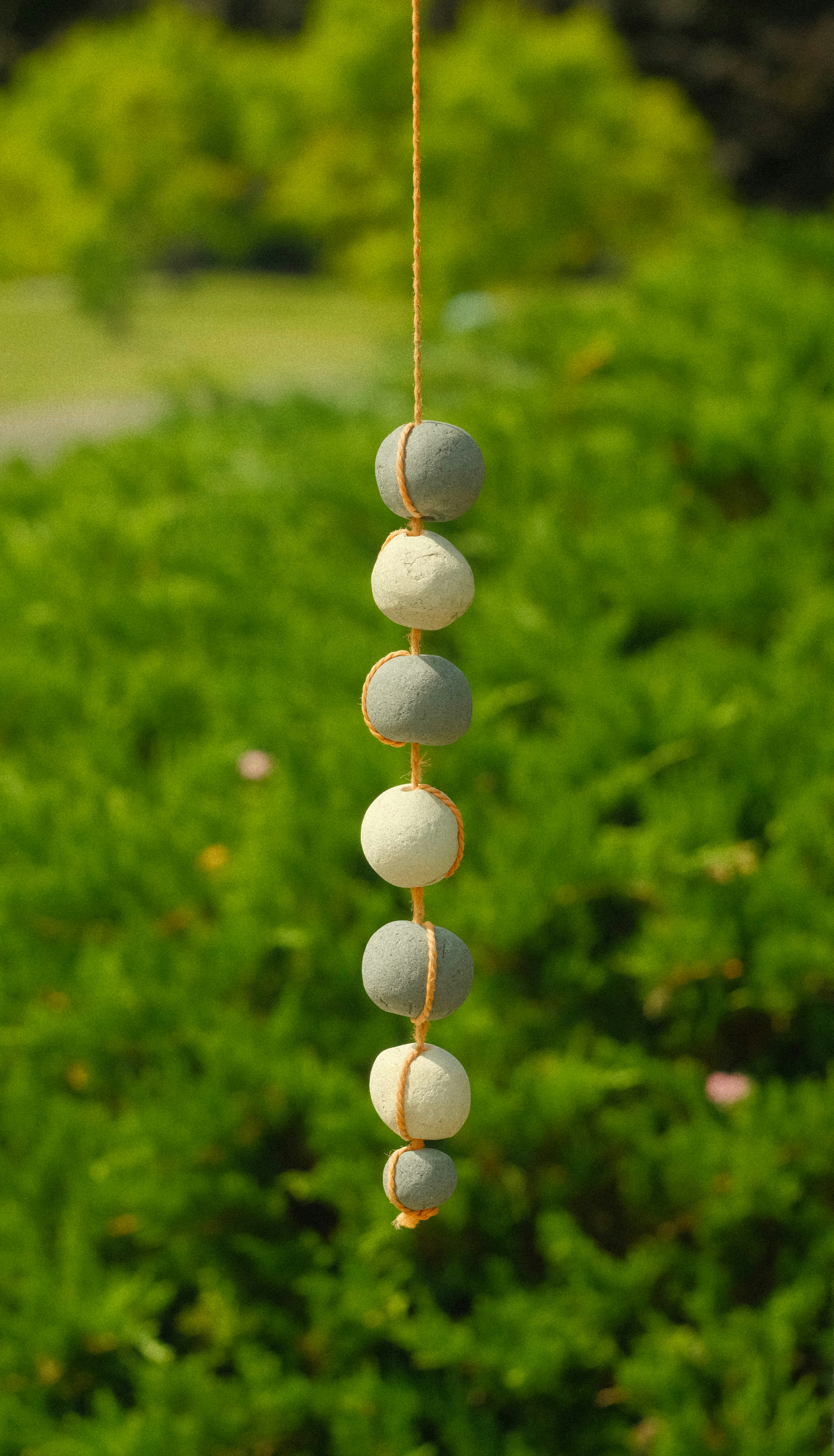 A wind chime hanging in front of a bush
