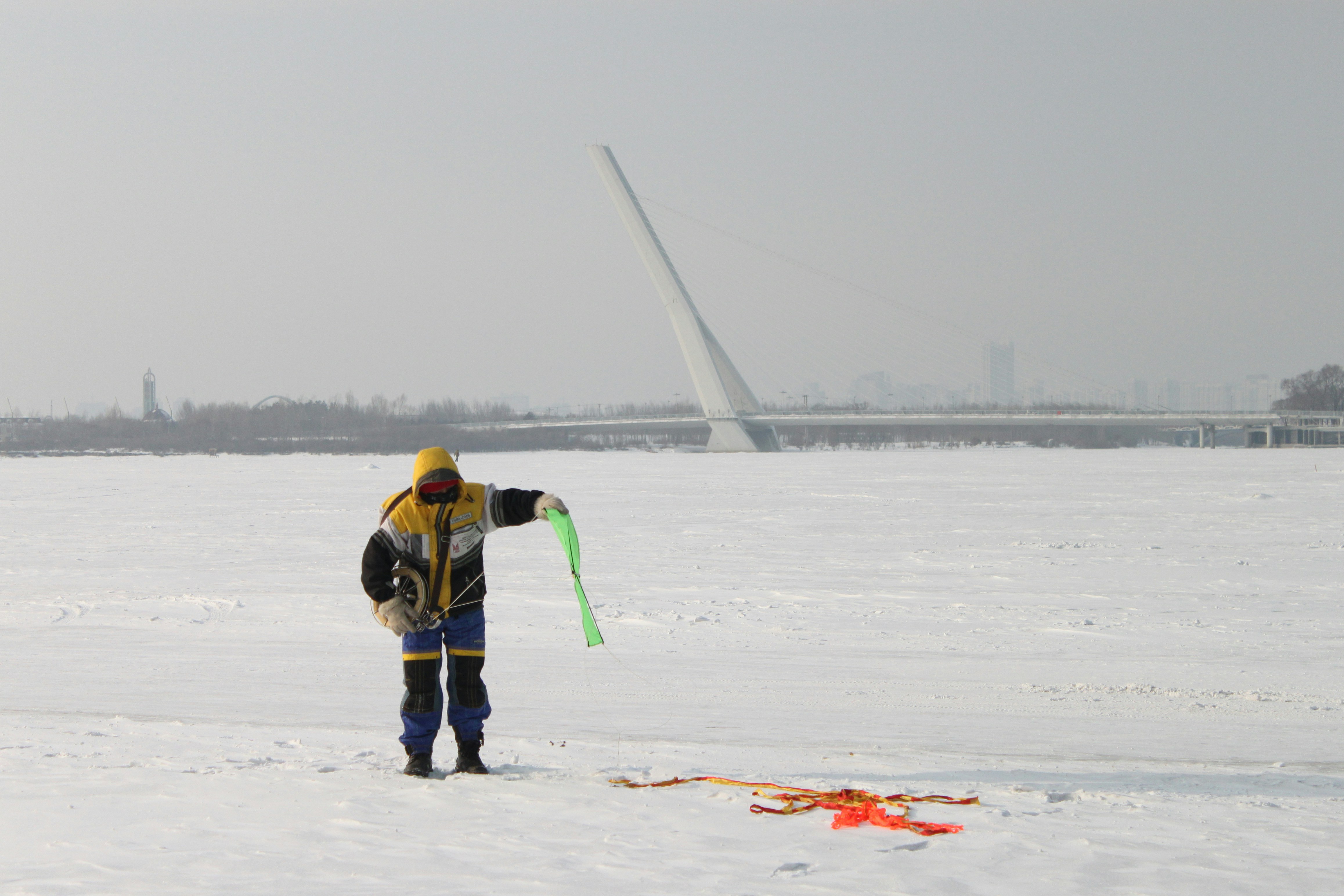 A man standing in the snow holding a kite