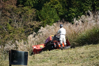 A man riding on the back of a red lawn mower