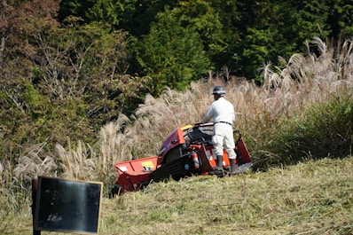 A man riding on the back of a red lawn mower