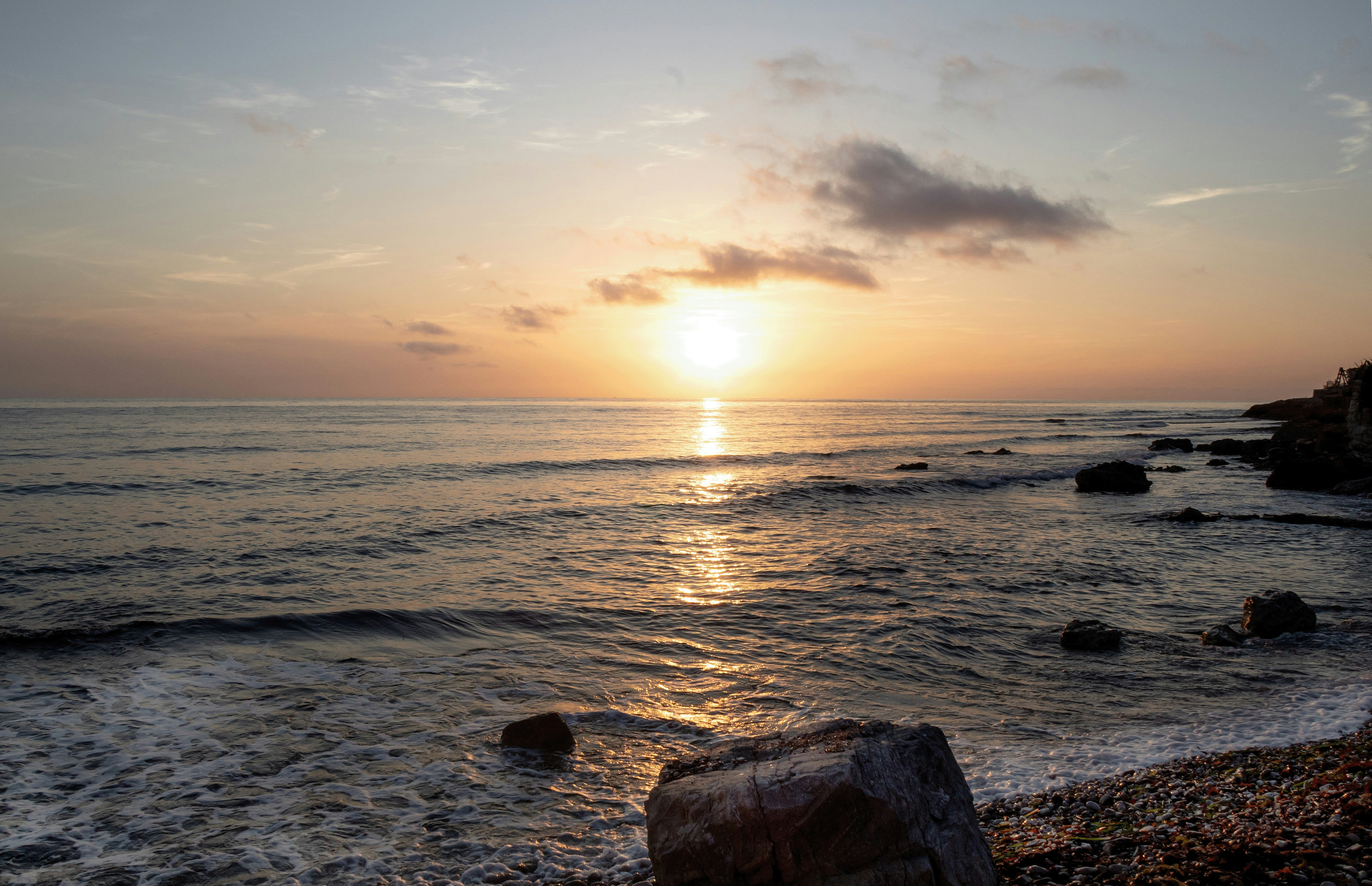The sun is setting over the ocean on the beach