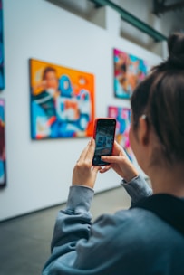 A woman looking at a cell phone in an art gallery