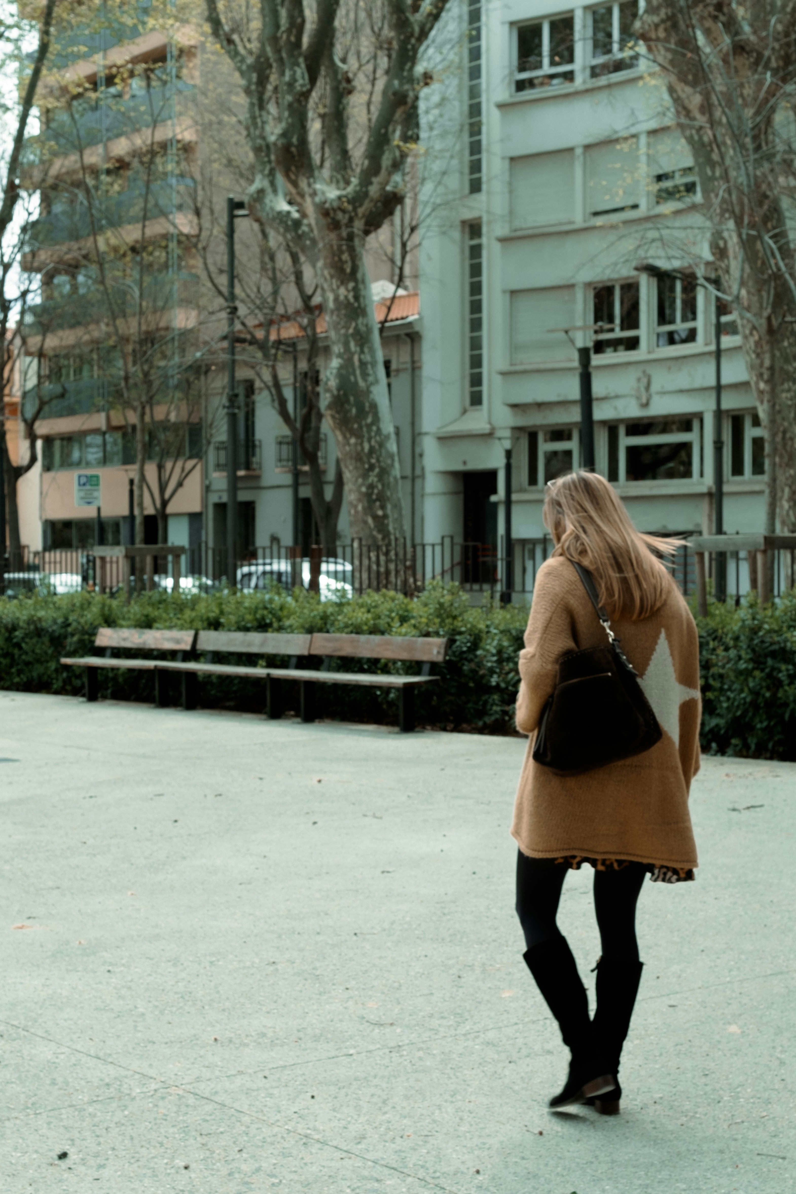 A woman walking down a street next to tall buildings