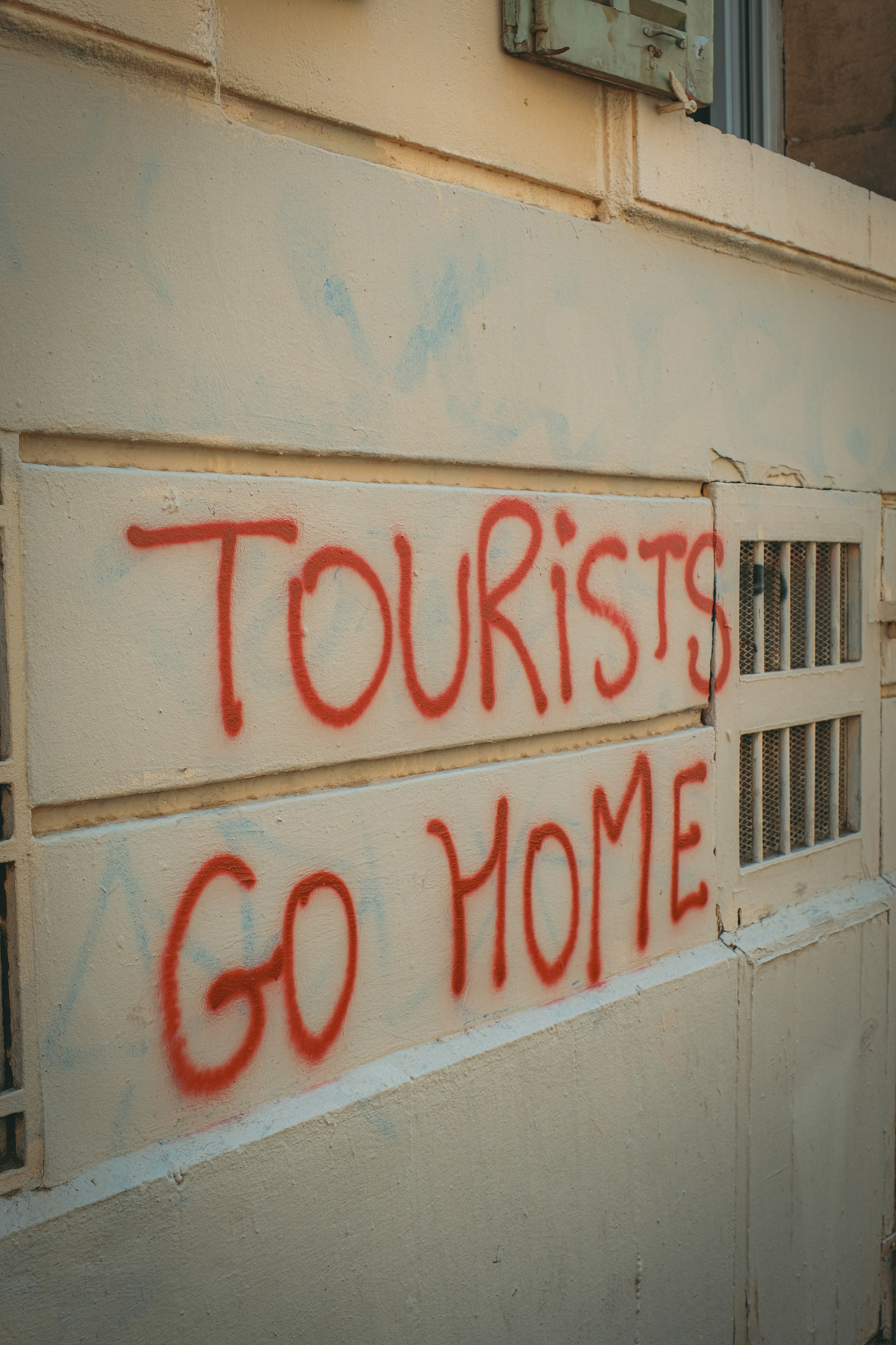 Graffiti on the side of a building that says tourists go home