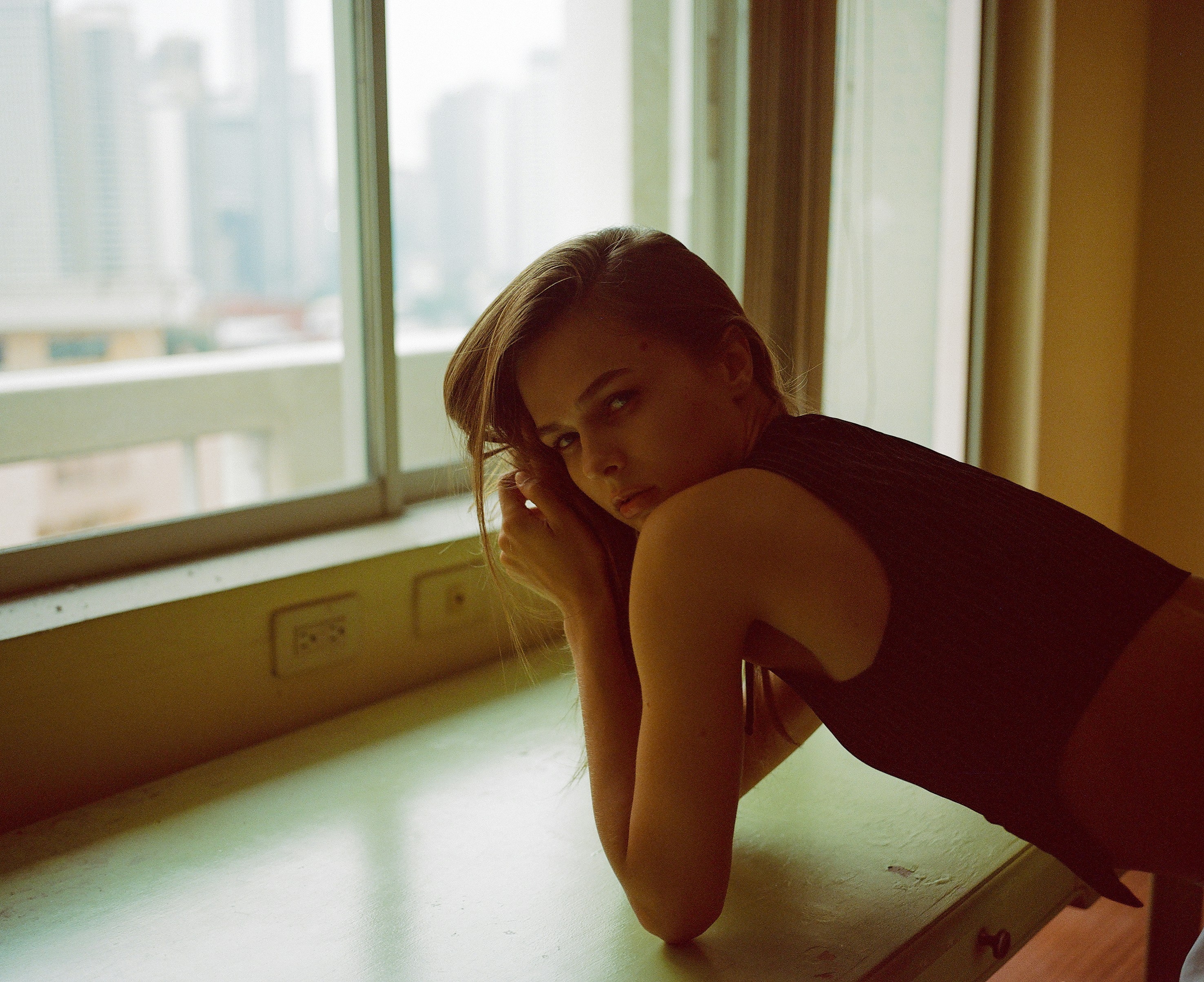 A woman leaning on a counter in front of a window