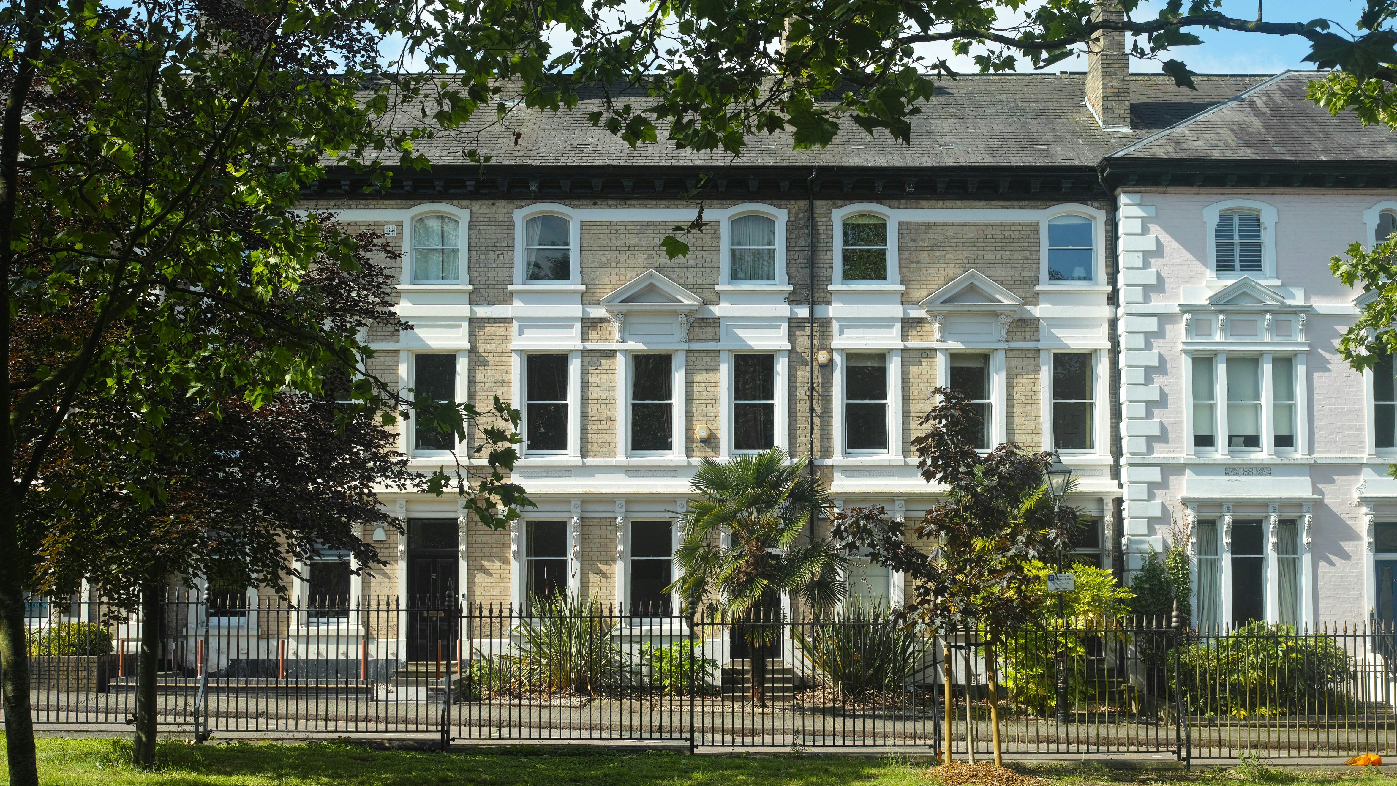 A large white building sitting next to a lush green park