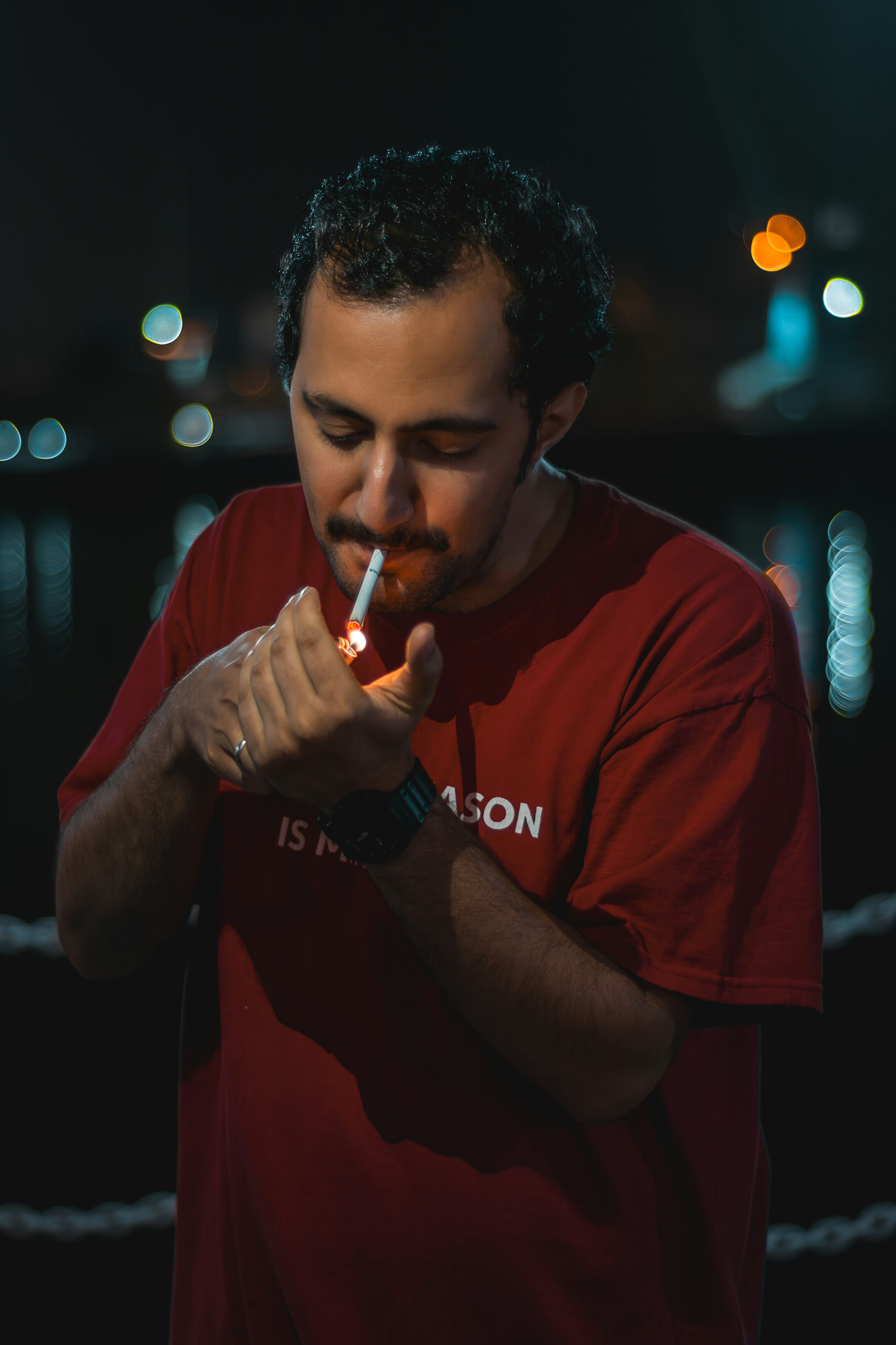 A man in a red shirt smoking a cigarette