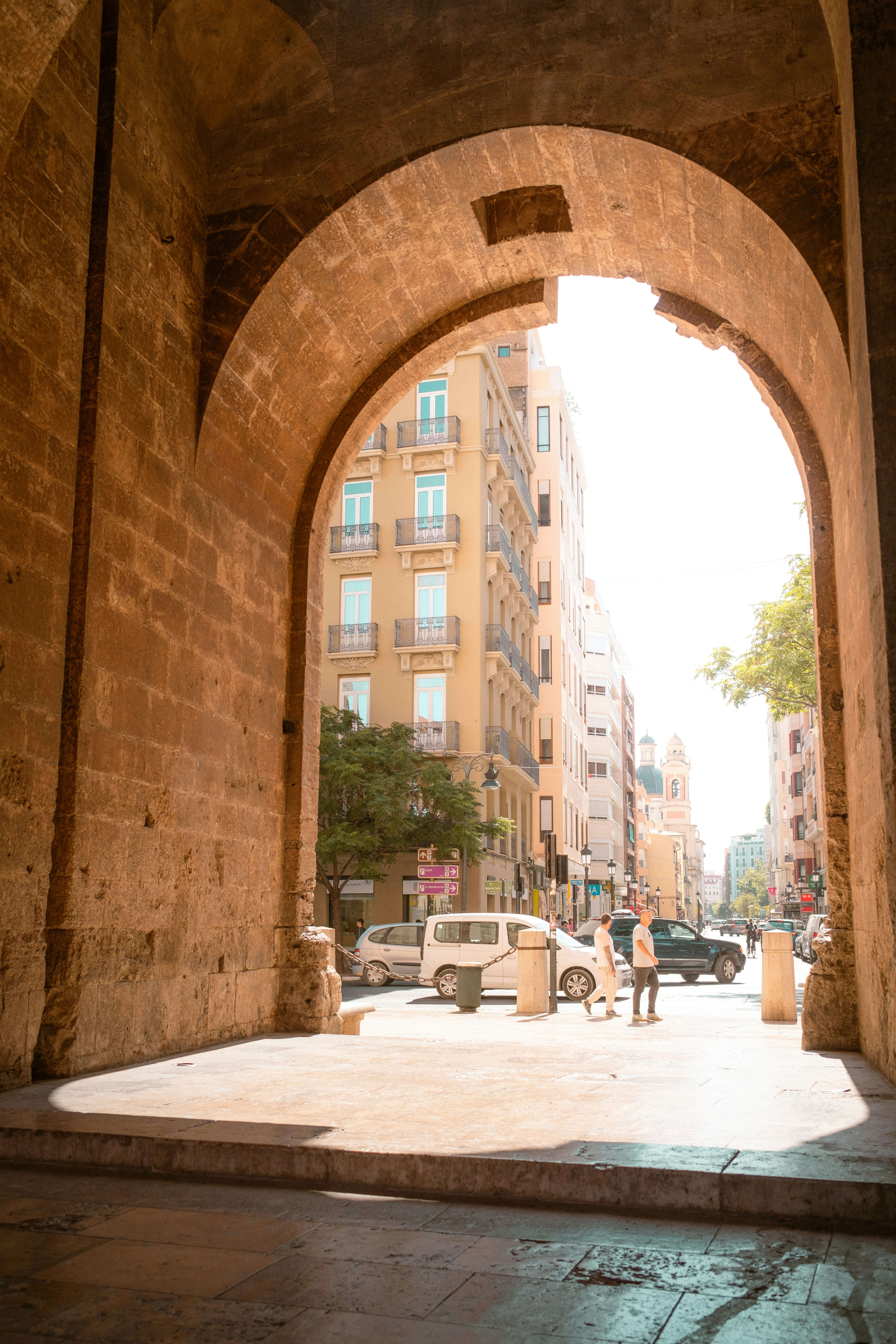 an-arch-in-a-stone-building-with-cars-parked-on-the-street-3Cyx3gRU29Y
