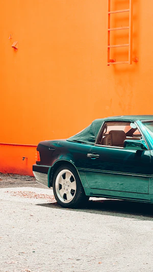 A green car parked in front of an orange building