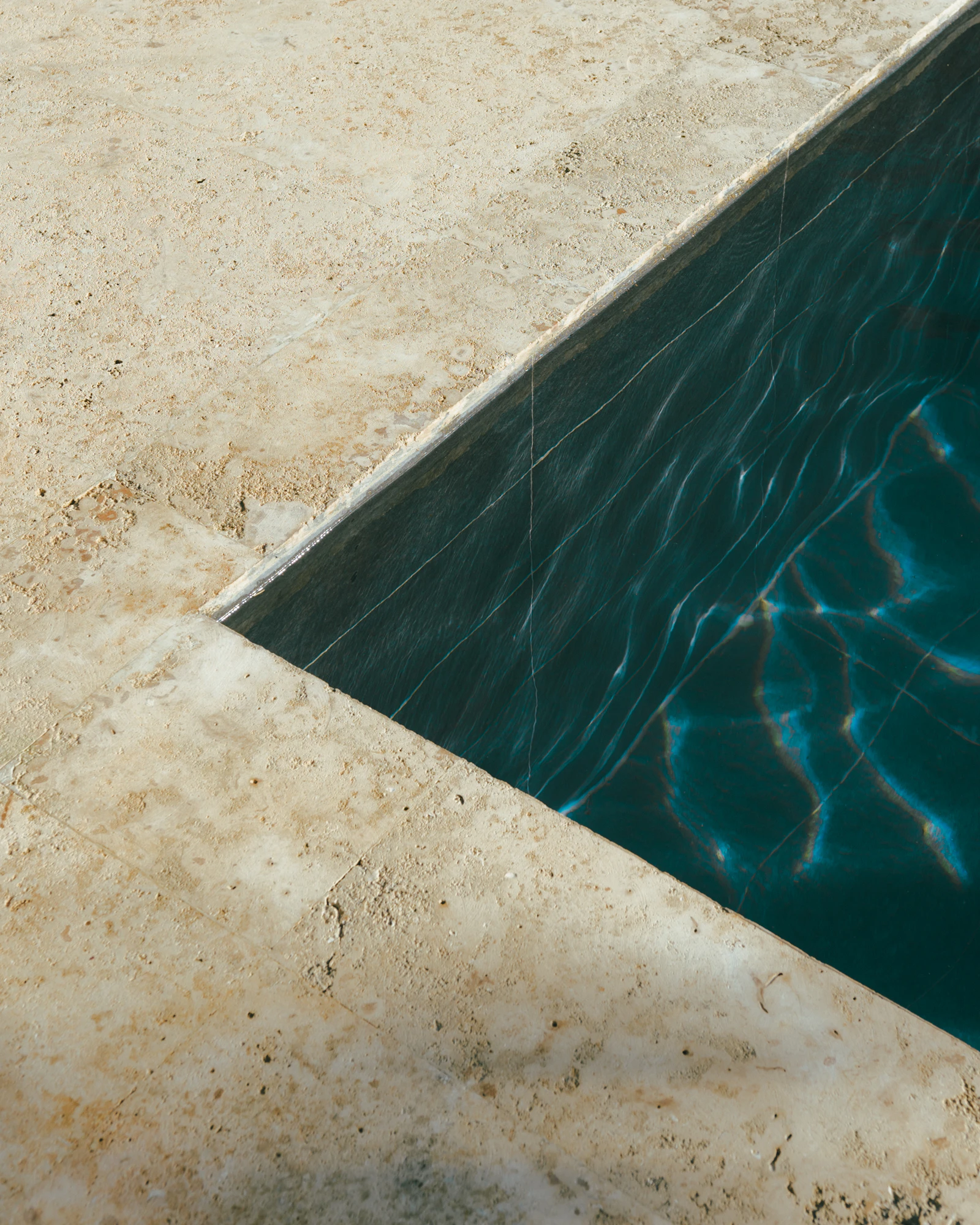 An empty resort swimming pool with loungers around it, the kind of Jamaican hotel capacity still sitting offline while room inventory rebuilds after Hurricane Melissa