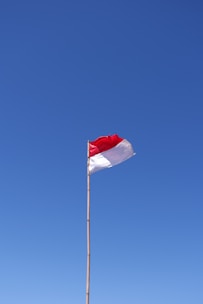 A red and white flag flying in the wind