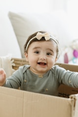 A baby girl sitting in a cardboard box