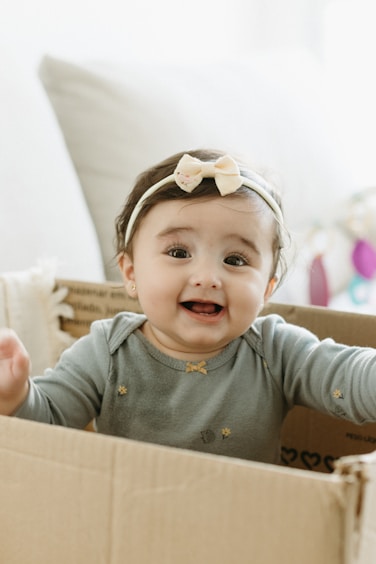 A baby girl sitting in a cardboard box
