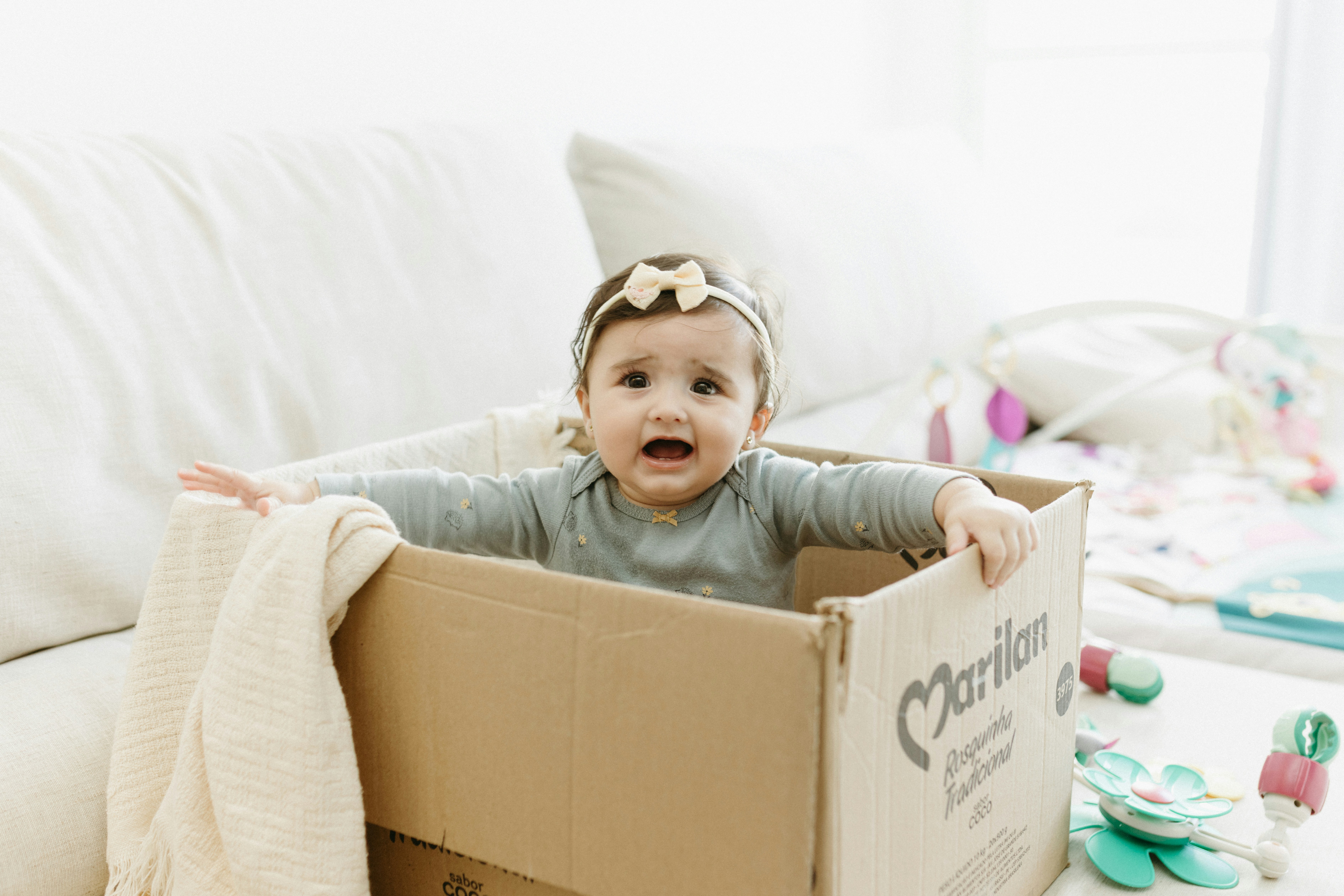 A baby in a cardboard box on the floor