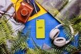 A book, headphones, a camera, and a cell phone on a table
