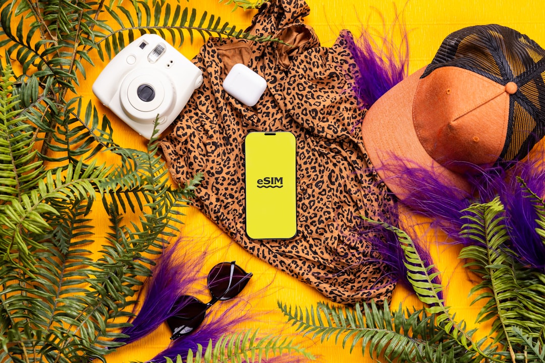 A cell phone laying on top of a lush green plant, eSIM service during summer vacation