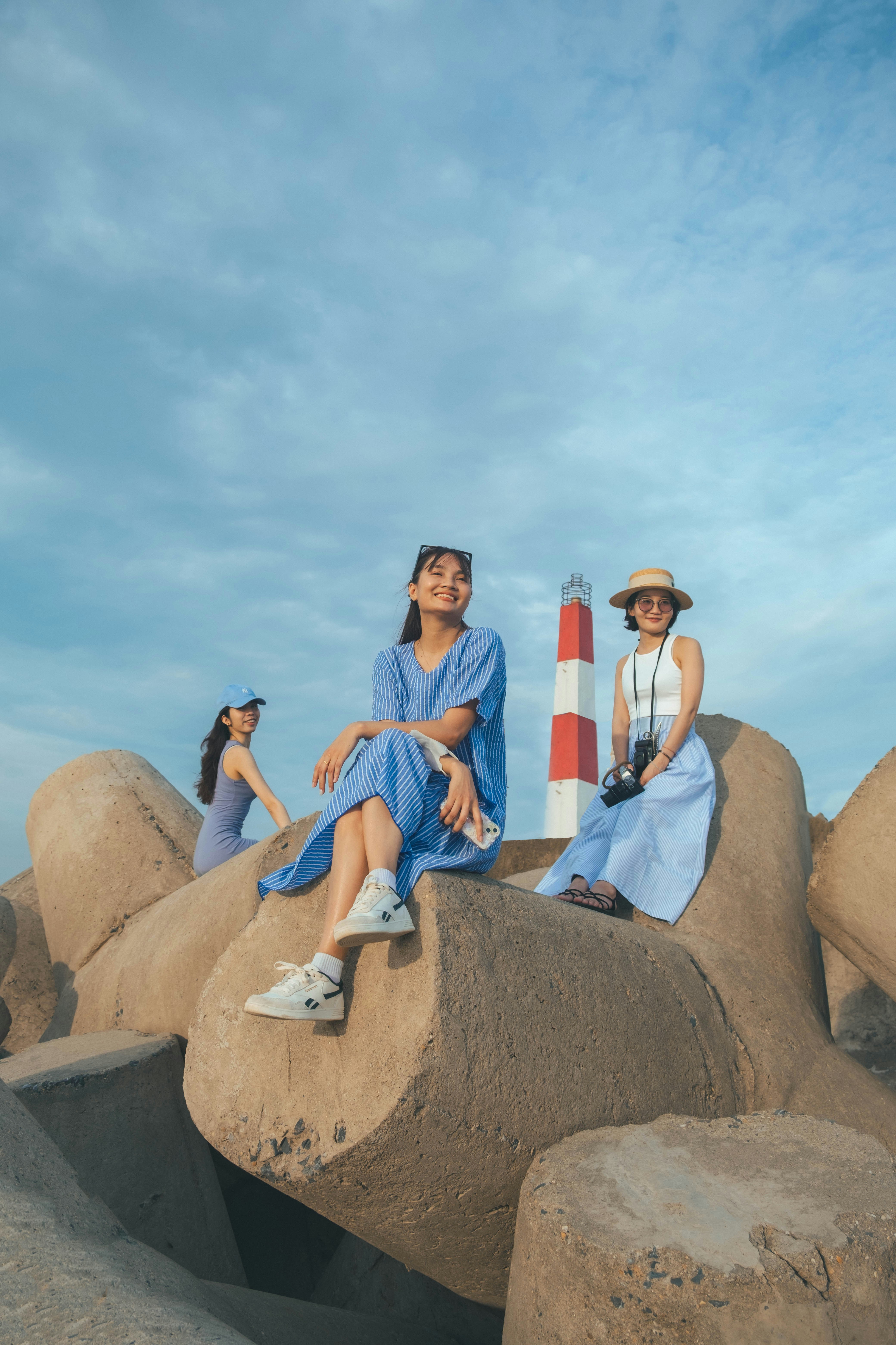 A couple of women sitting on top of rocks photo – Free Blue Image on ...