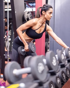 A woman doing a squat with dumbbells in a gym