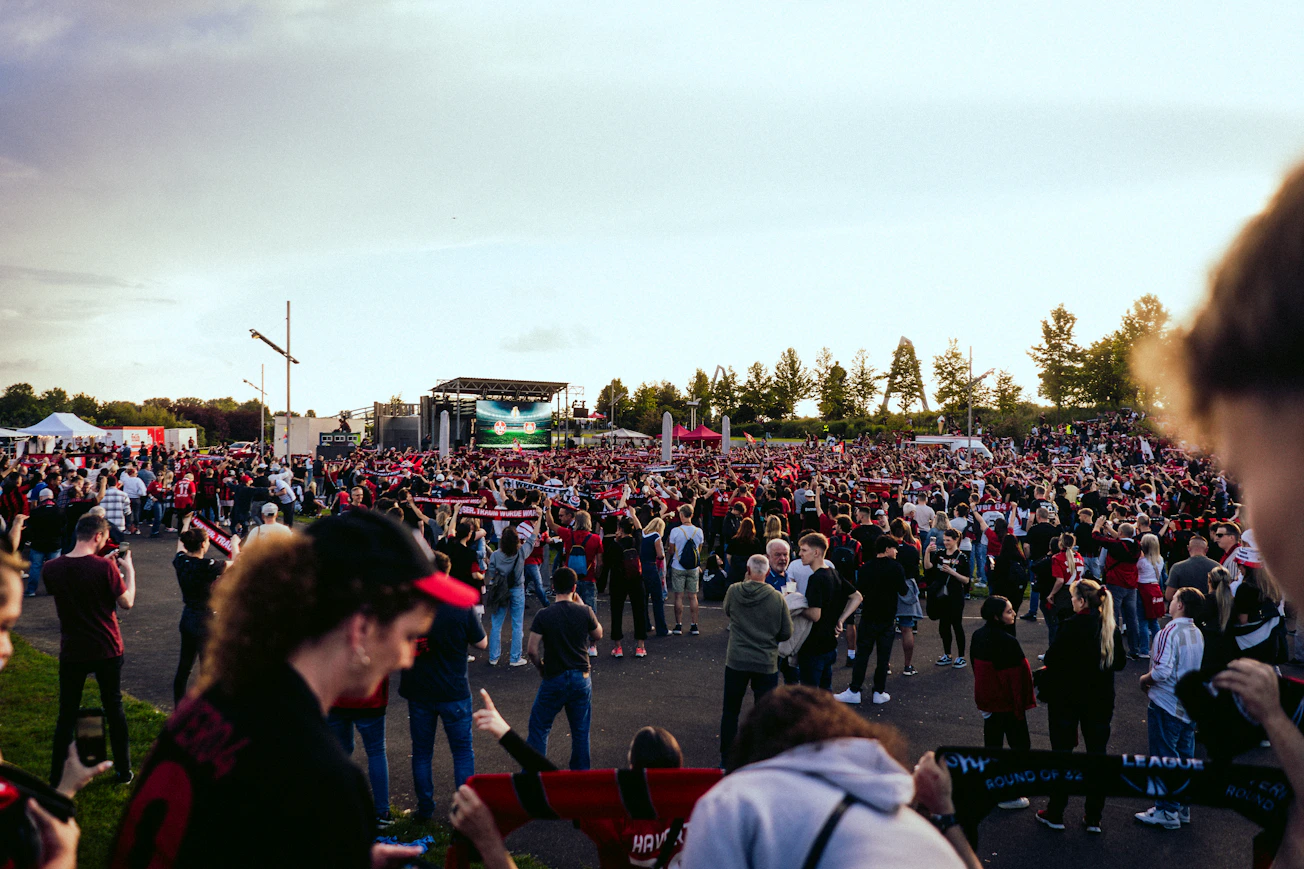 Aficionados al fútbol siguen un partido juntos durante un evento al aire libre