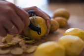 A person peeling a lemon with a pair of scissors