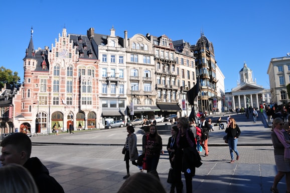 A group of people walking down a street next to tall buildings