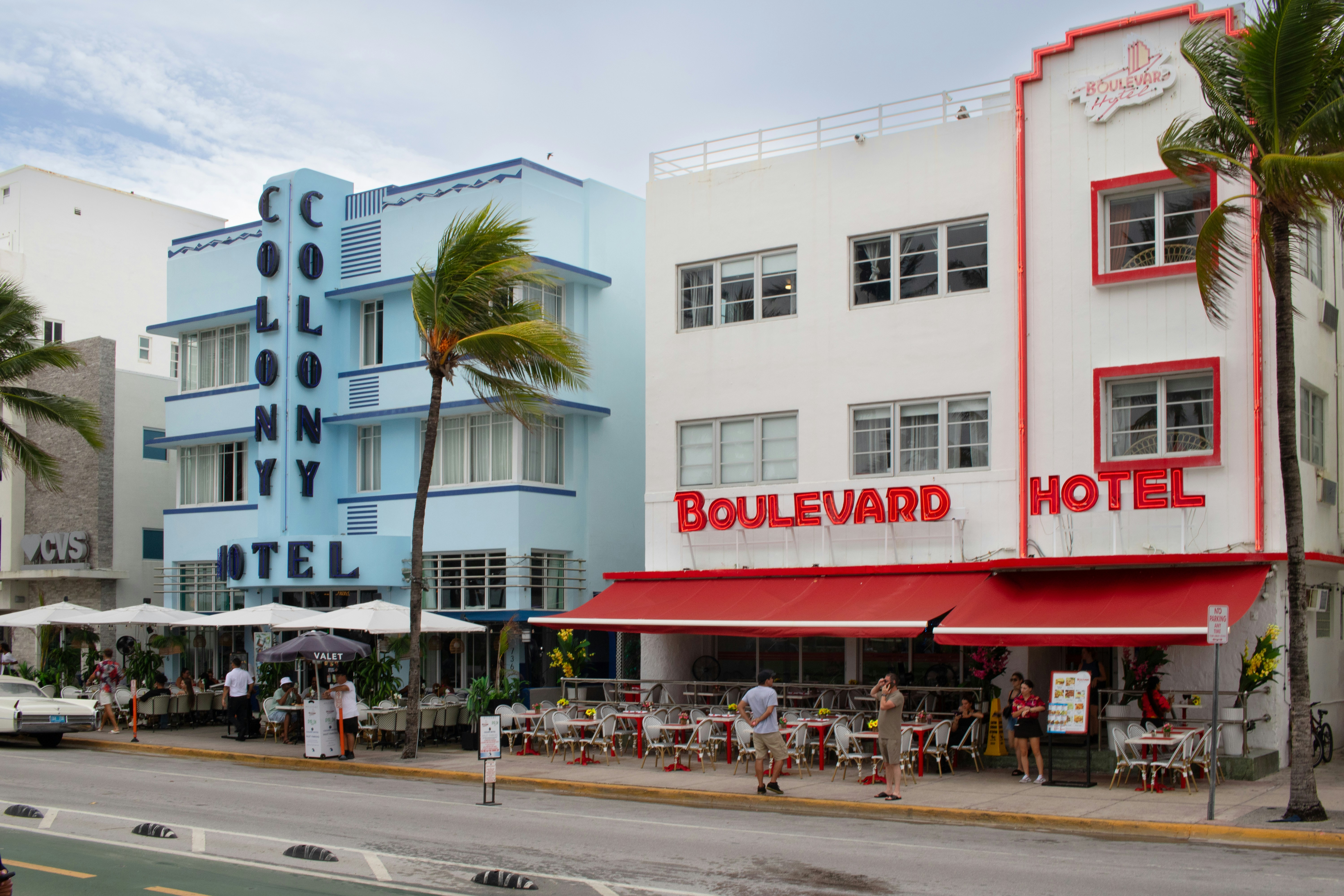 A street scene with a hotel and palm trees, Pictured here is the Colony Hotel and Boulevard Hotel on Miami Beach