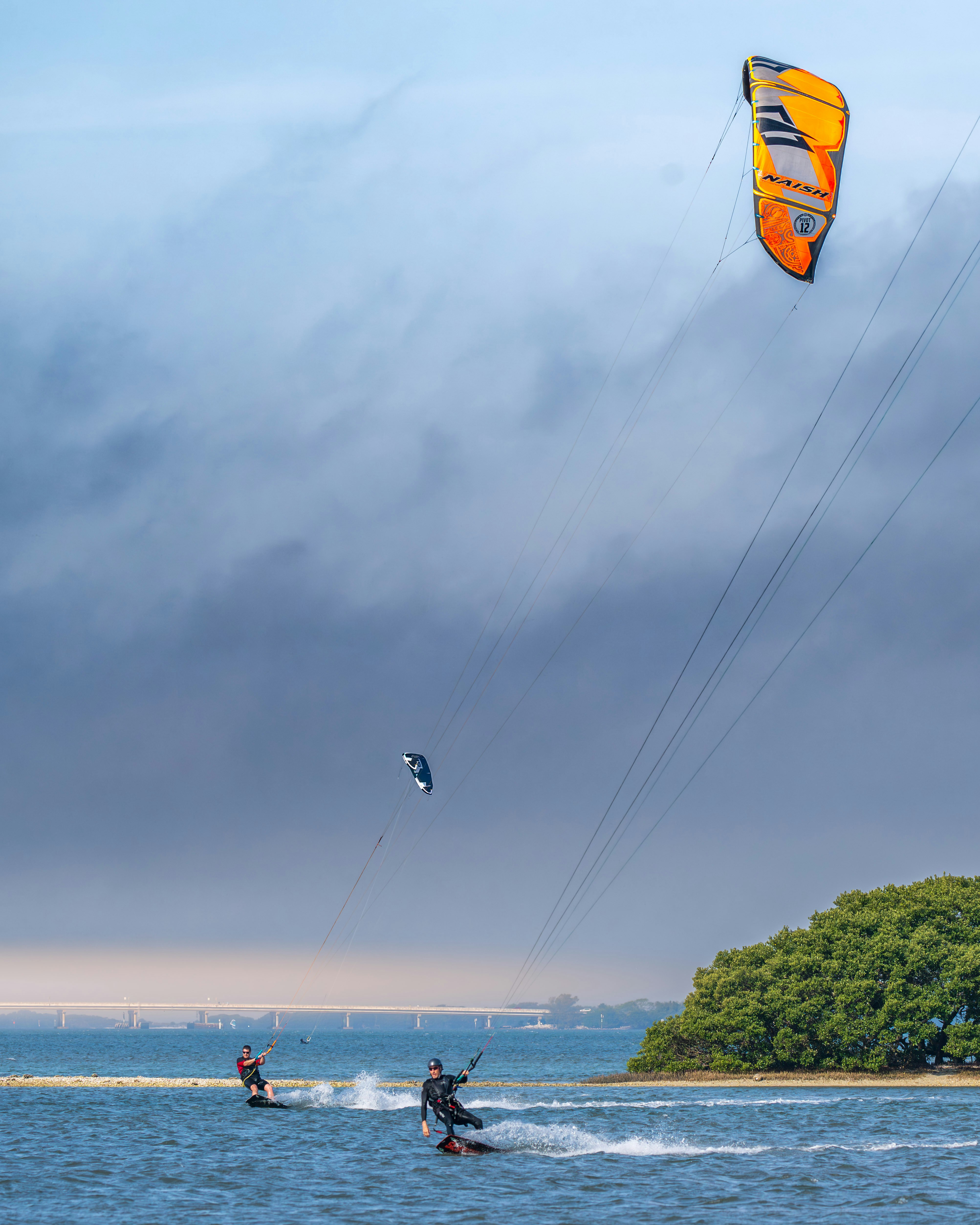 Two people parasailing in the ocean on a cloudy day