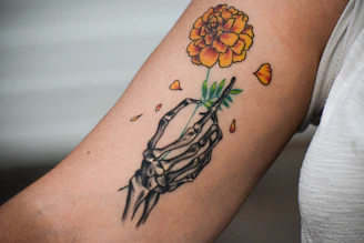 A person with a tattoo on their arm holding a flower