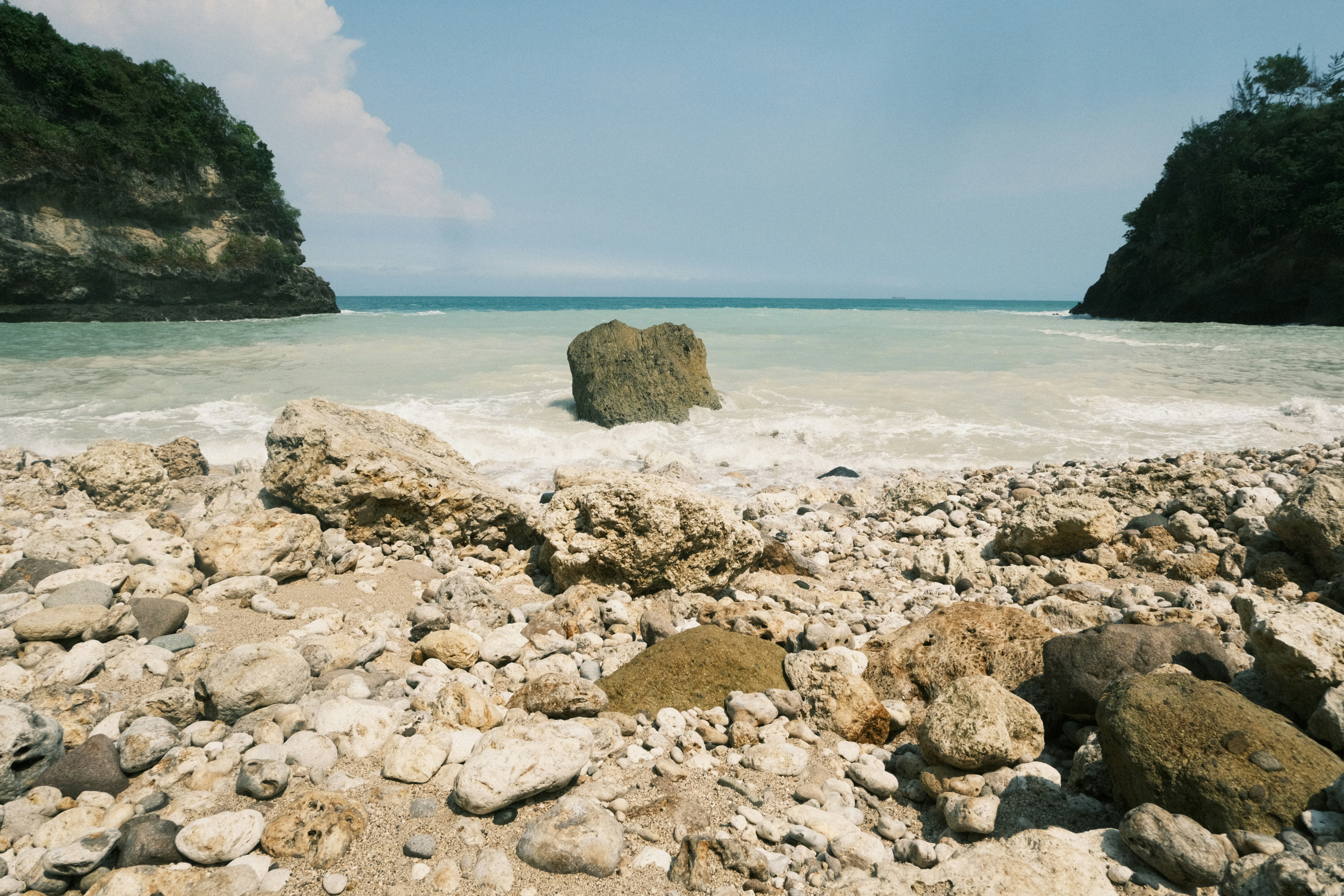 A rocky beach with a large rock in the middle of it