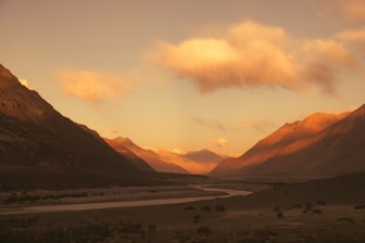 The sun is setting over a valley with mountains in the background
