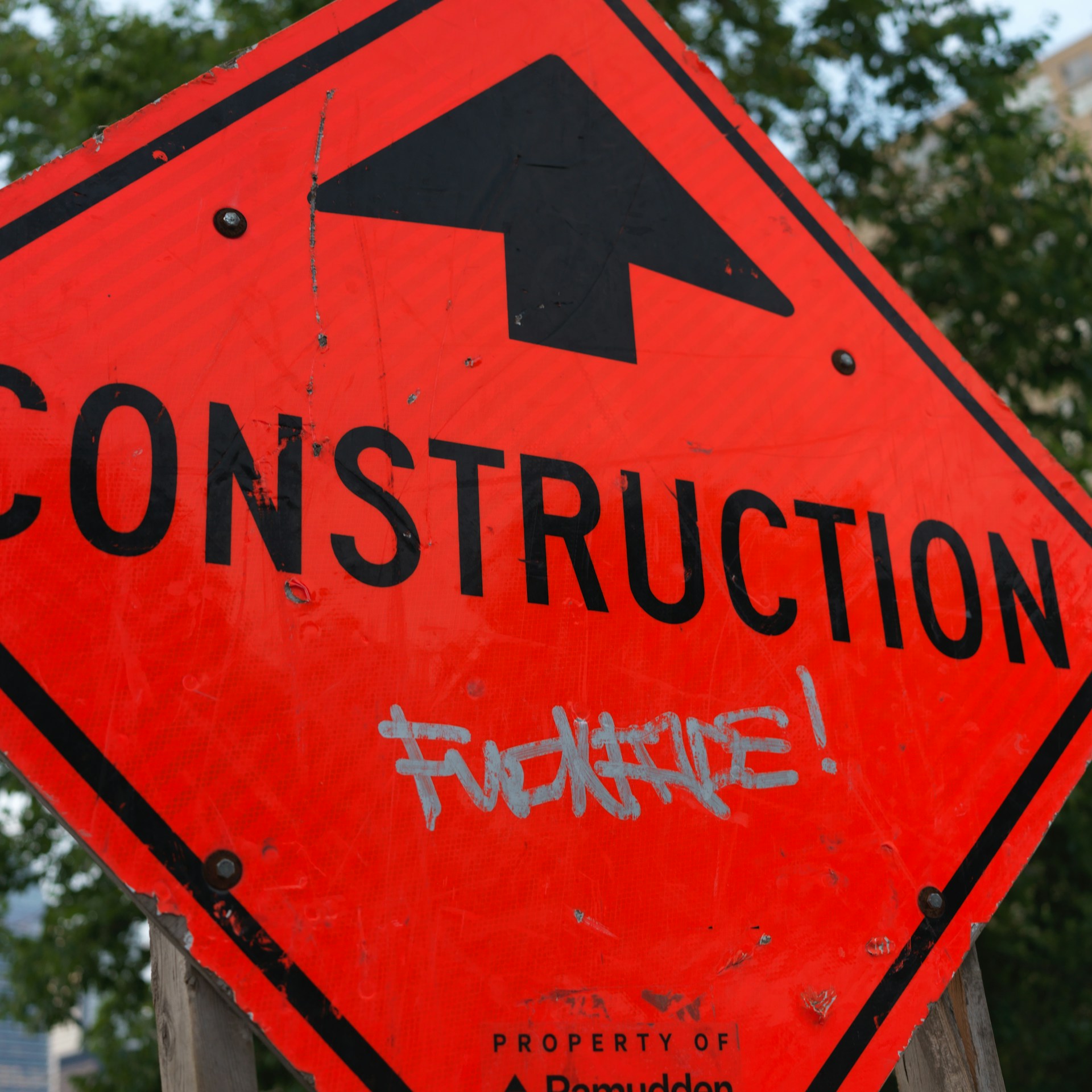 A red construction sign with a black arrow on it