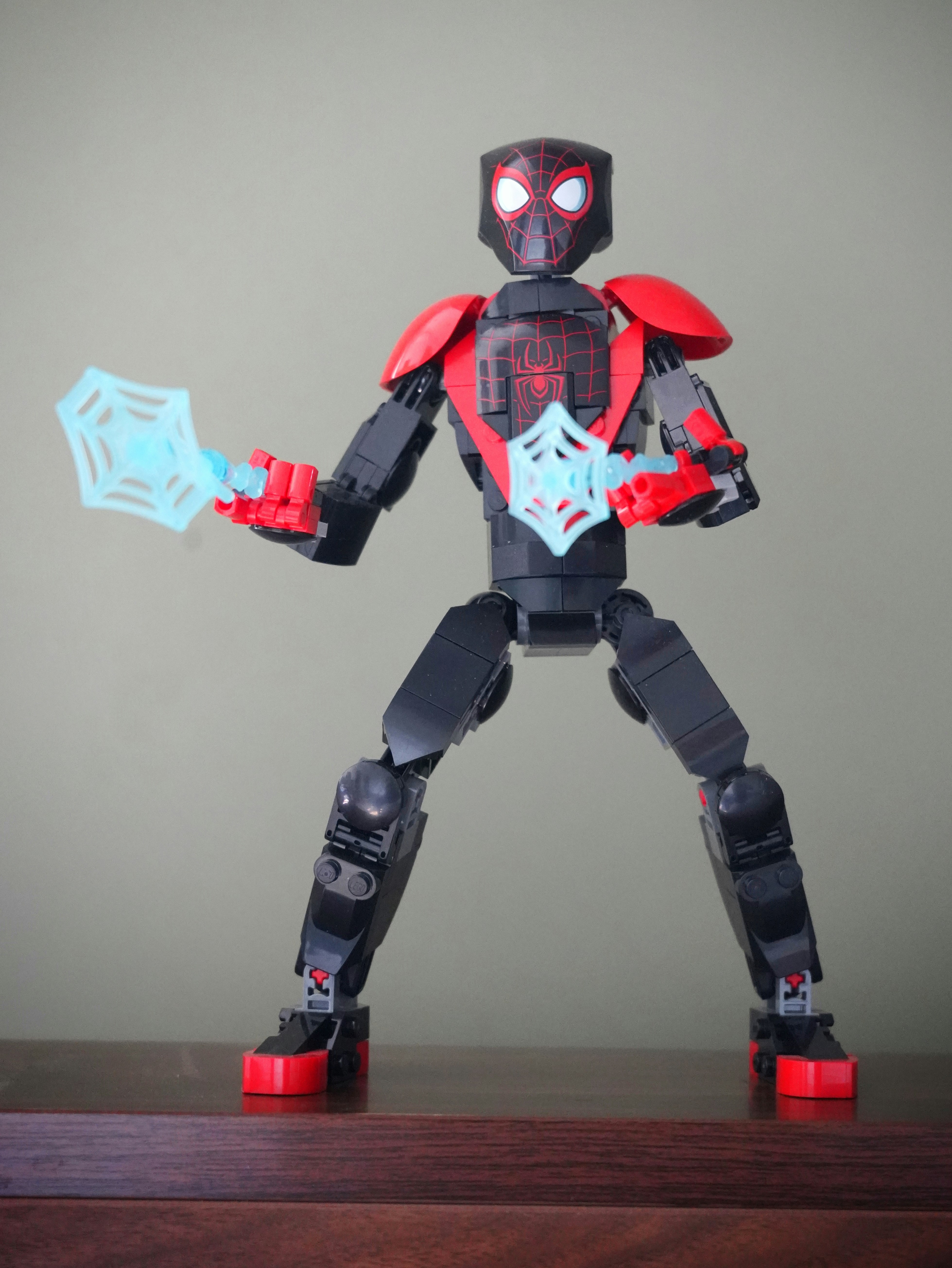 Miles Morales Spider-Man action figure in black and red suit with web shooting in dark atmospheric display
