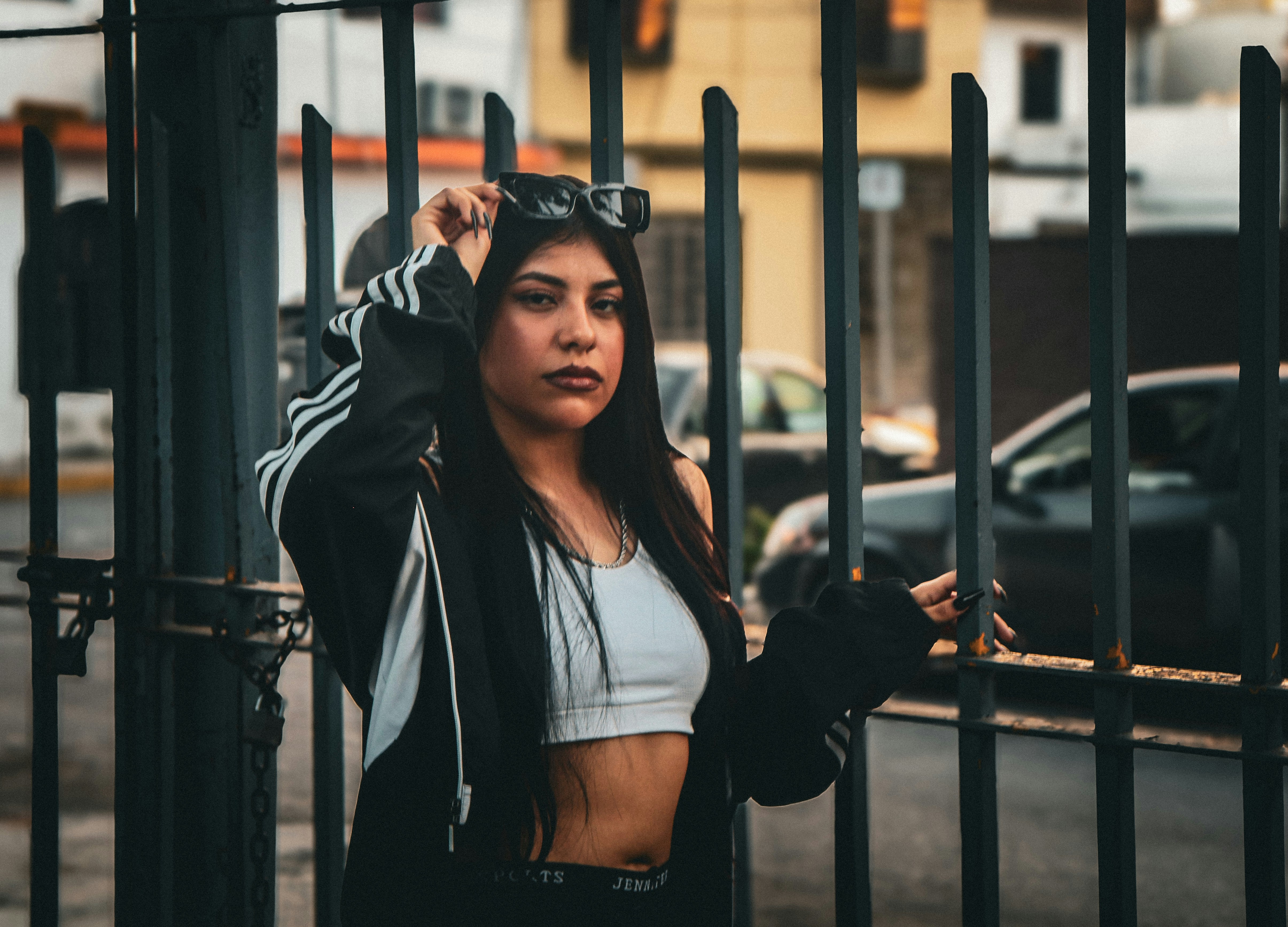 A woman is standing behind a fence with her hand on her head