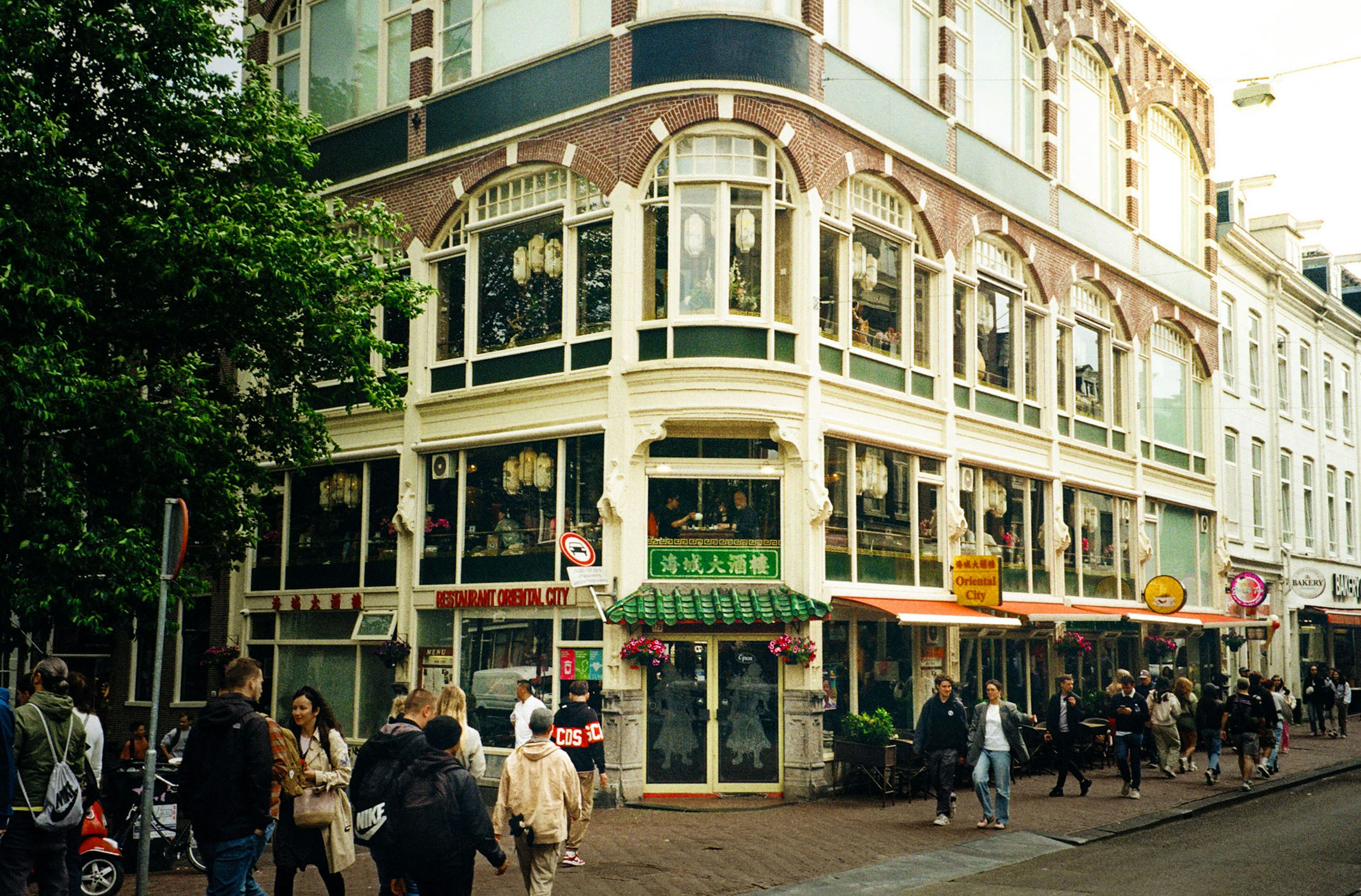 A group of people walking down a street next to tall buildings