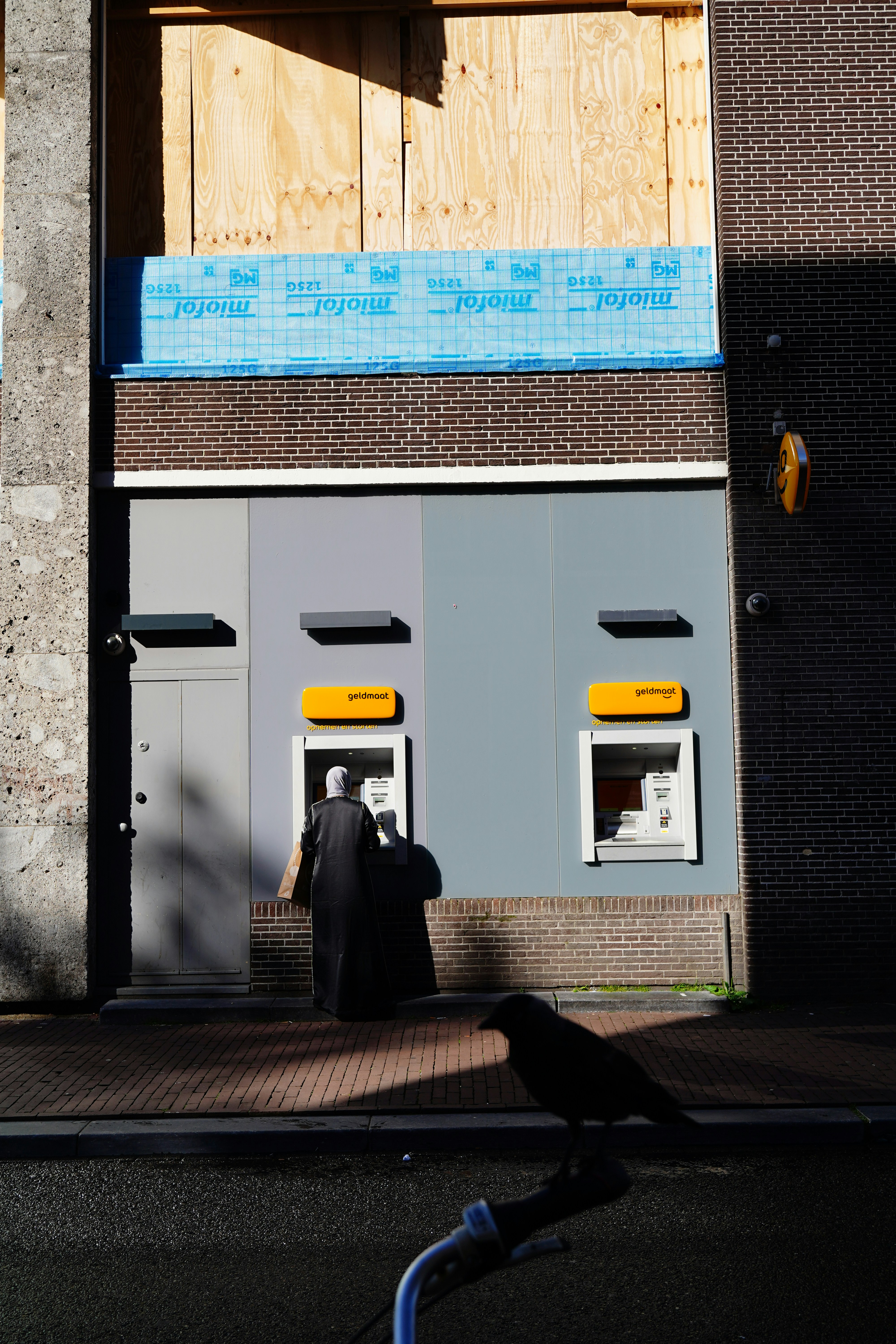 A man walking down a street past a tall building
