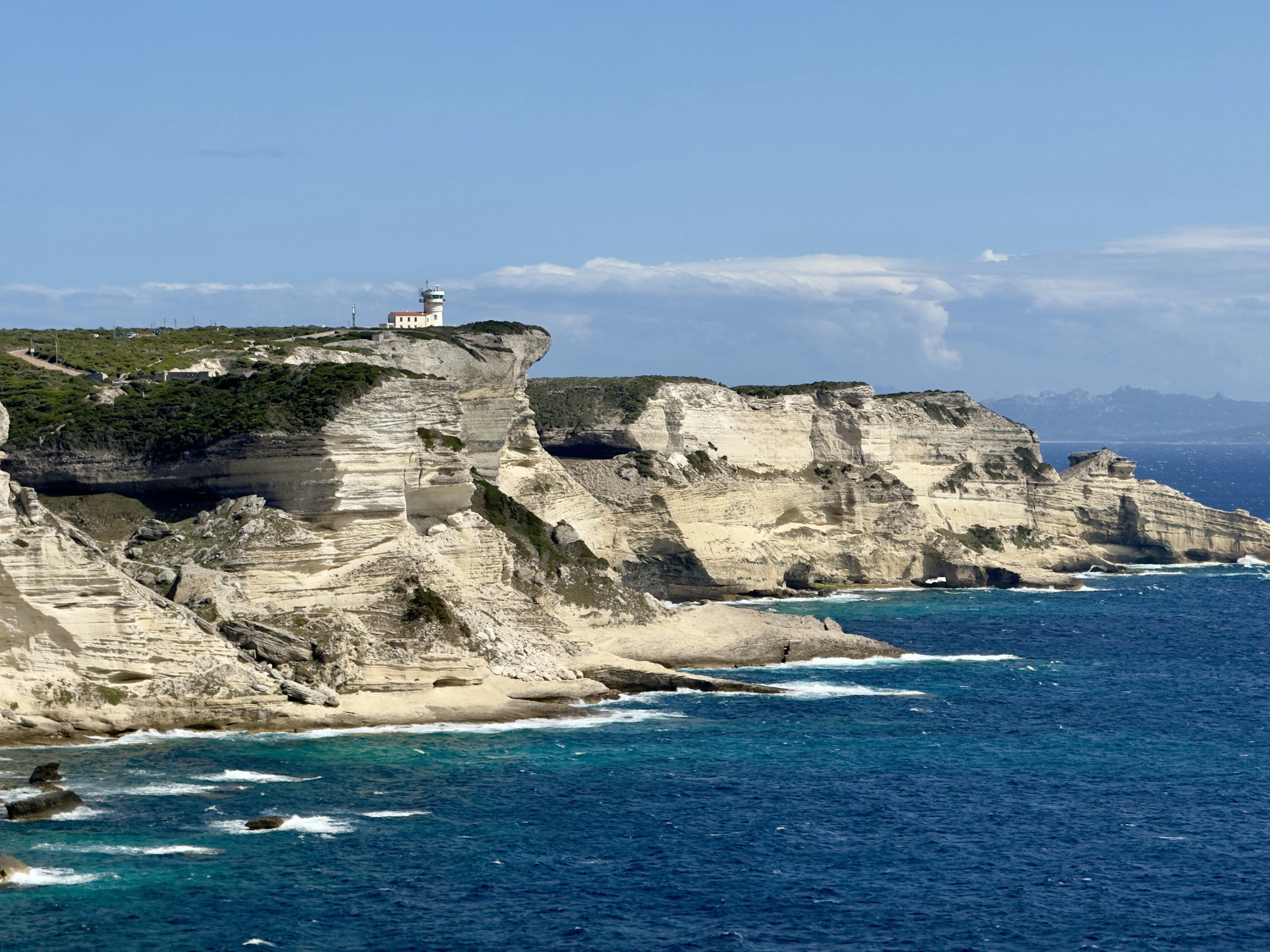 A view of a rocky coastline with a lighthouse on top of it