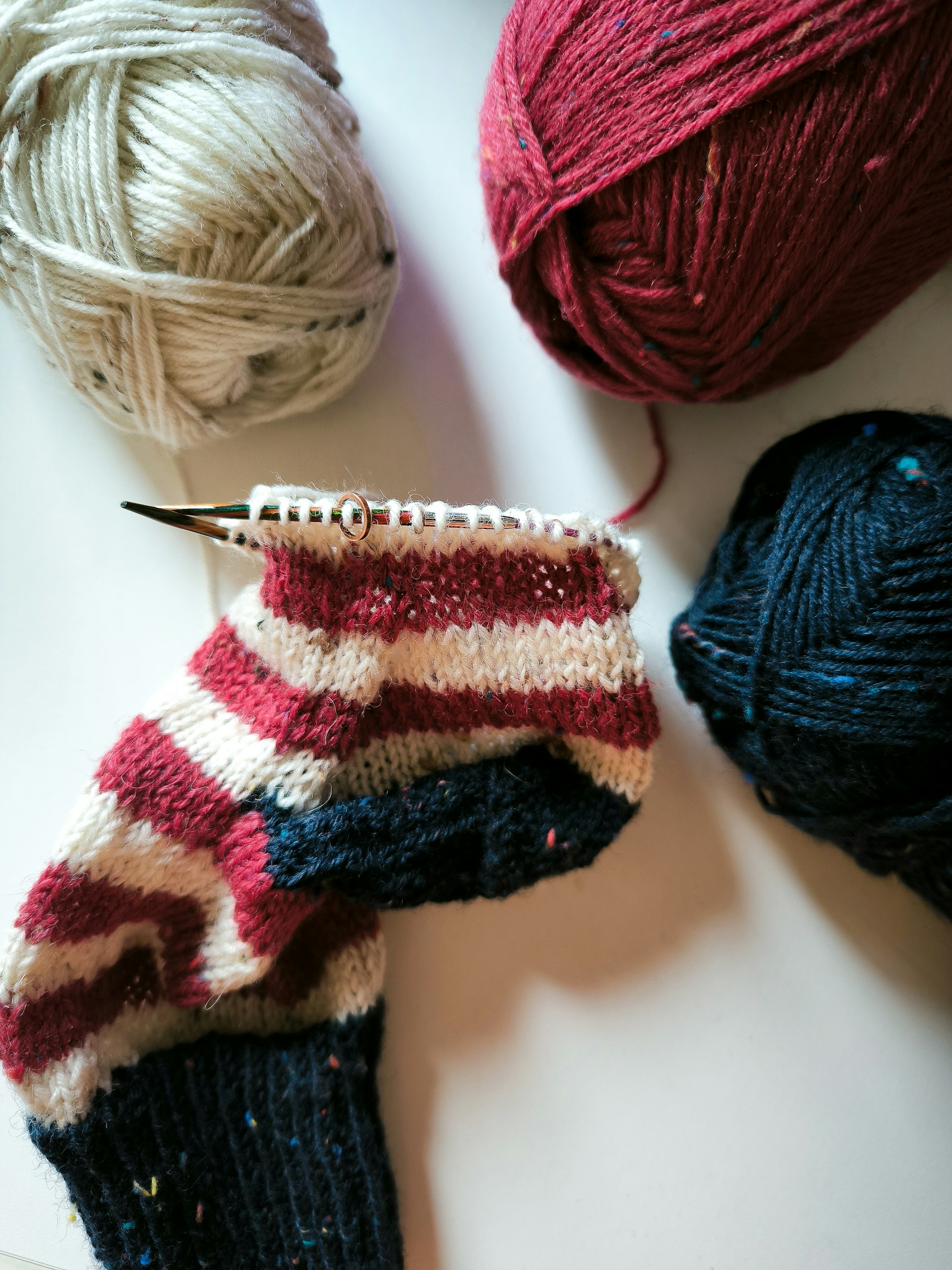 Three balls of yarn and a pair of scissors on a table