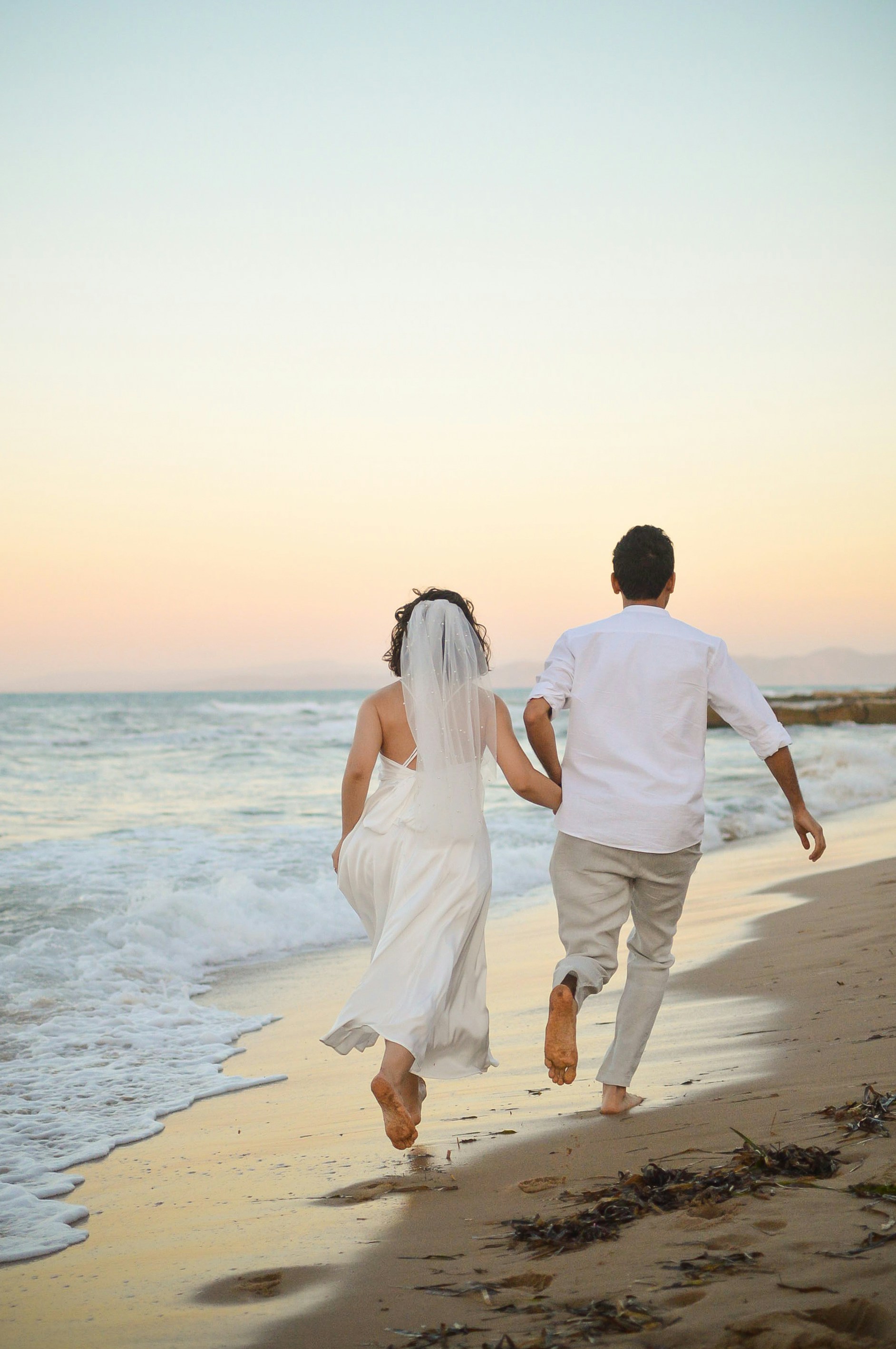 A bride and groom running on the beach